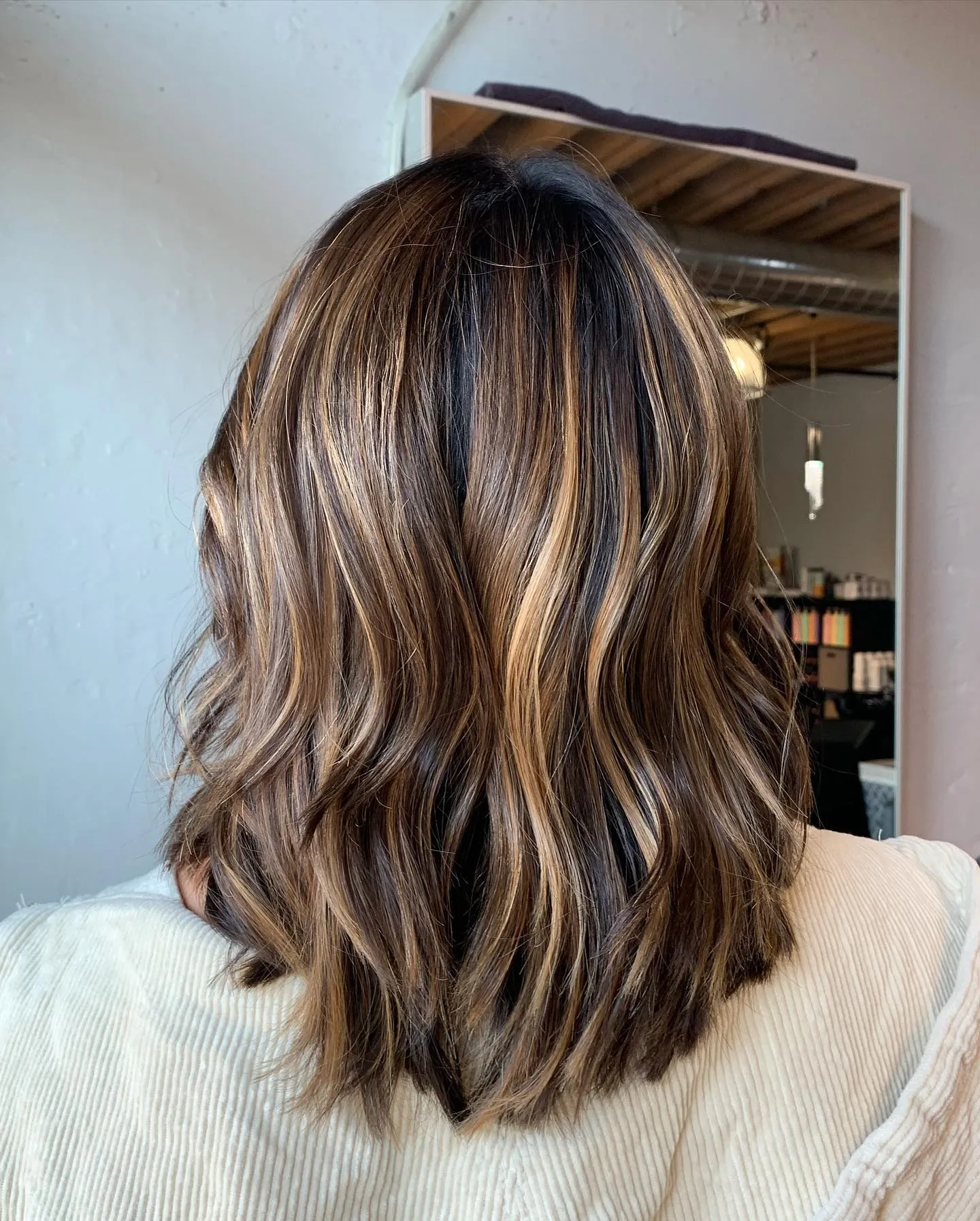 Medium brown lob with warm blonde highlights and waves