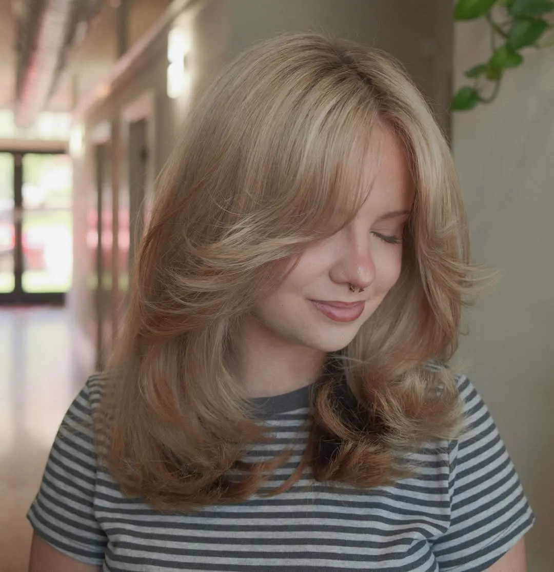 Soft golden blonde with face-framing layers and curtain bangs