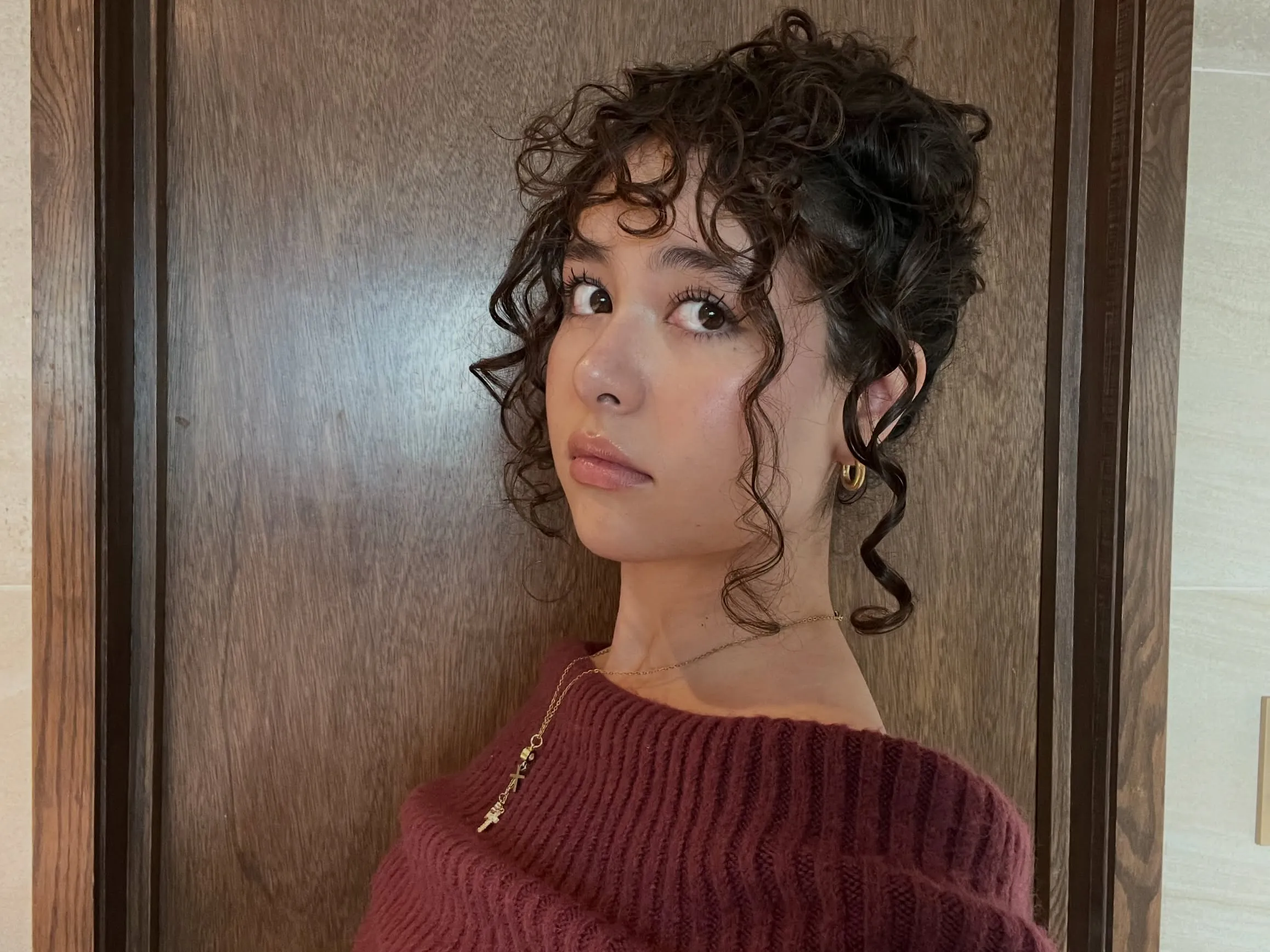 Loose curly updo with face-framing tendrils