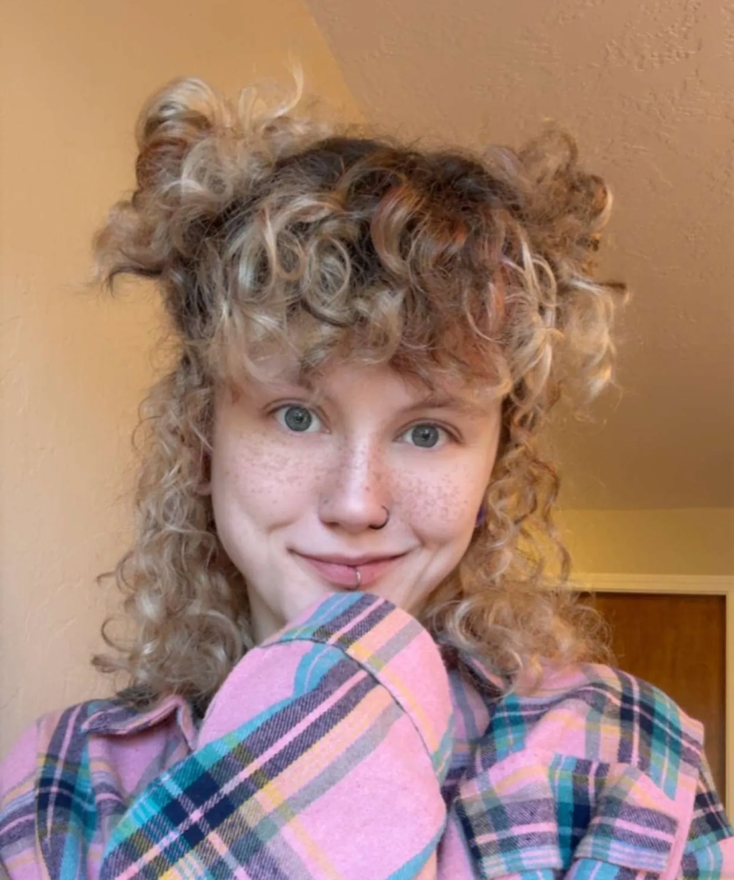 Half-up curly space buns with loose curls and bangs