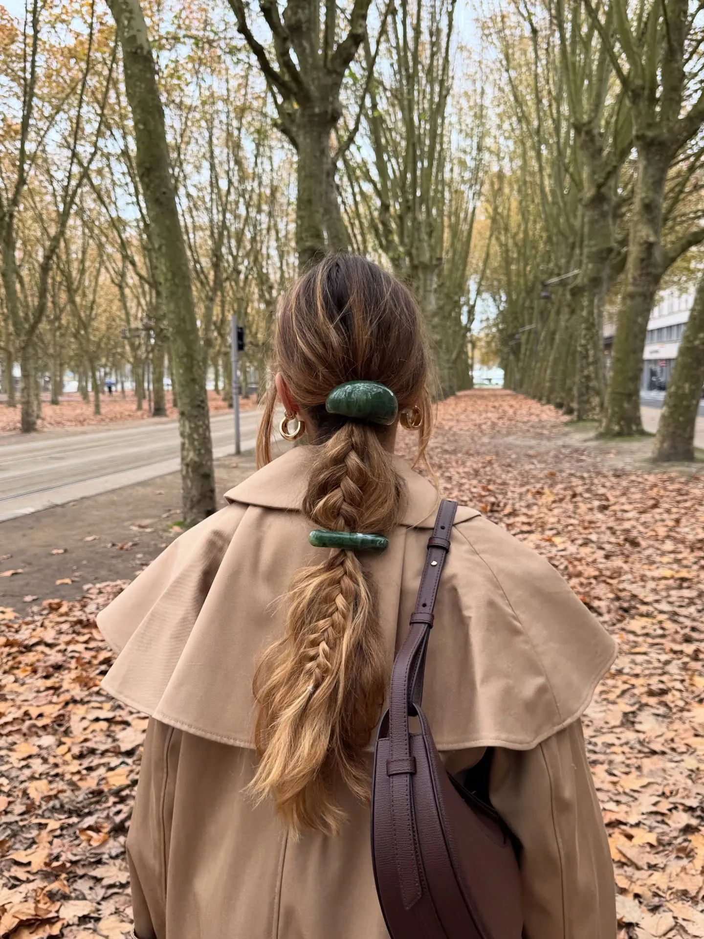 Long low ponytail braid secured with two green hair clips