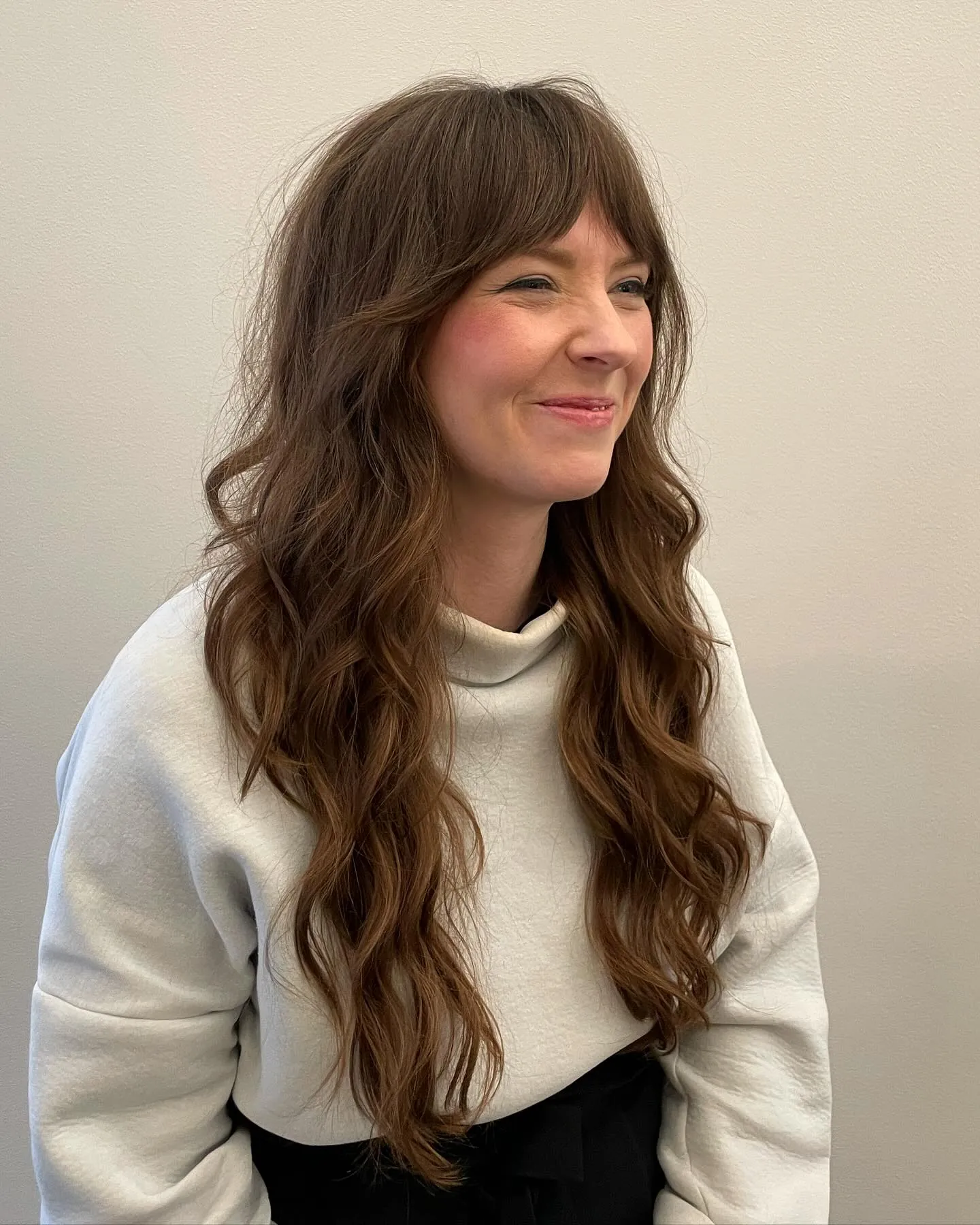Long brunette waves with a full soft fringe and layered ends