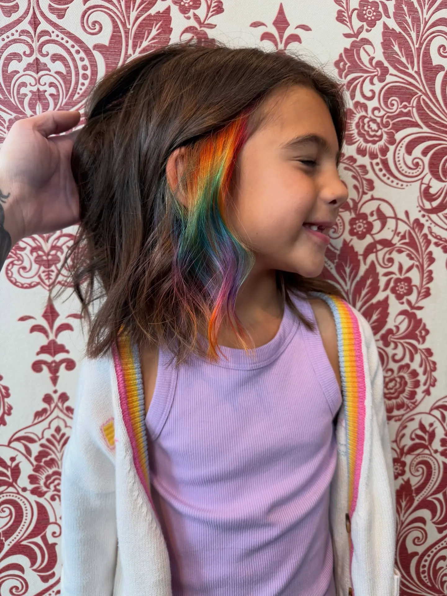 Brown shoulder-length hair with rainbow peekaboo colour underneath