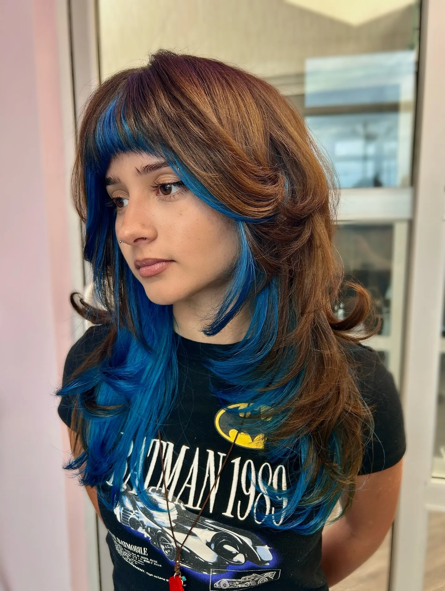 Layered brown hair with vivid blue peekaboo sections around the face