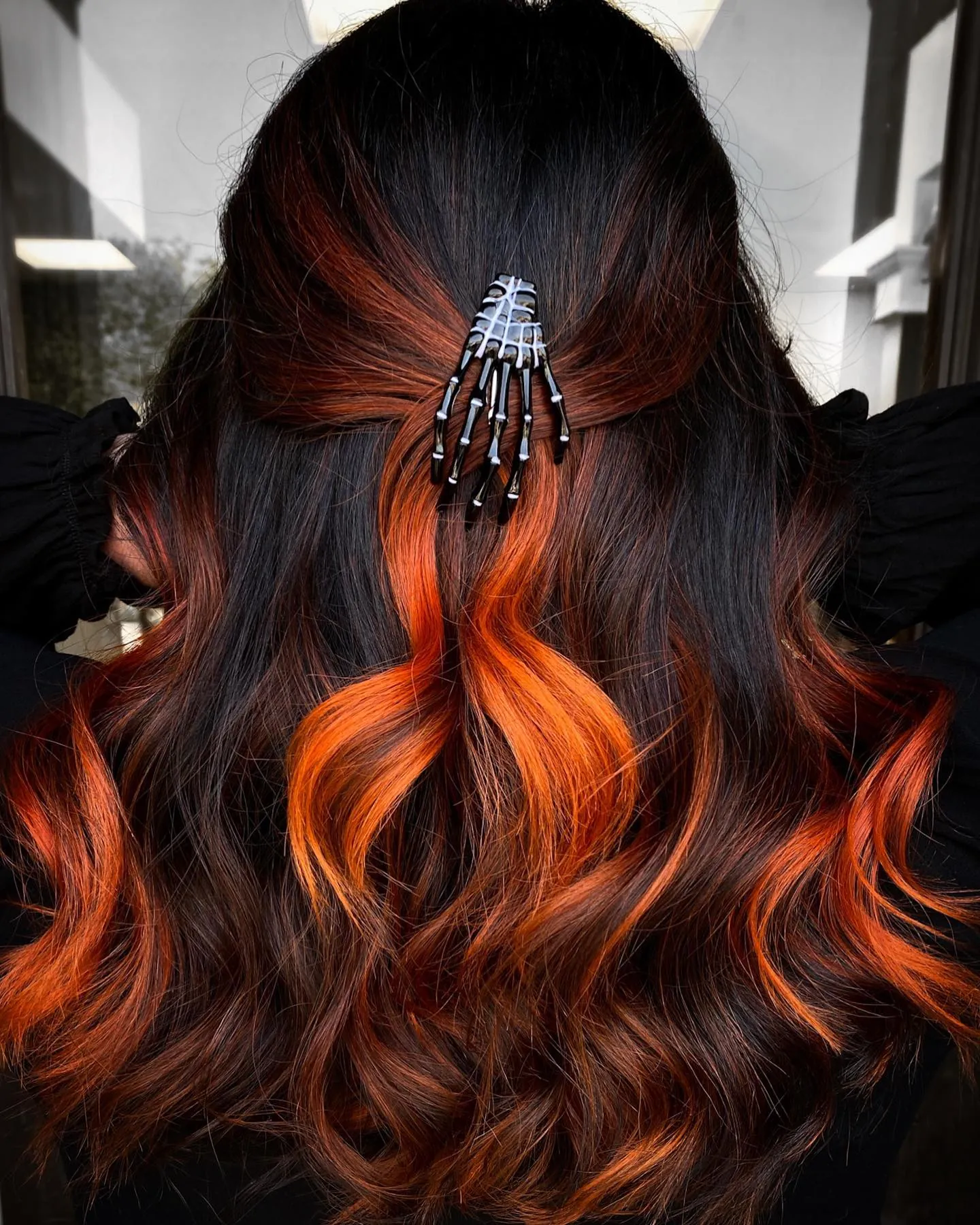 Half-up curled hair with a skeleton hand claw clip and orange pieces