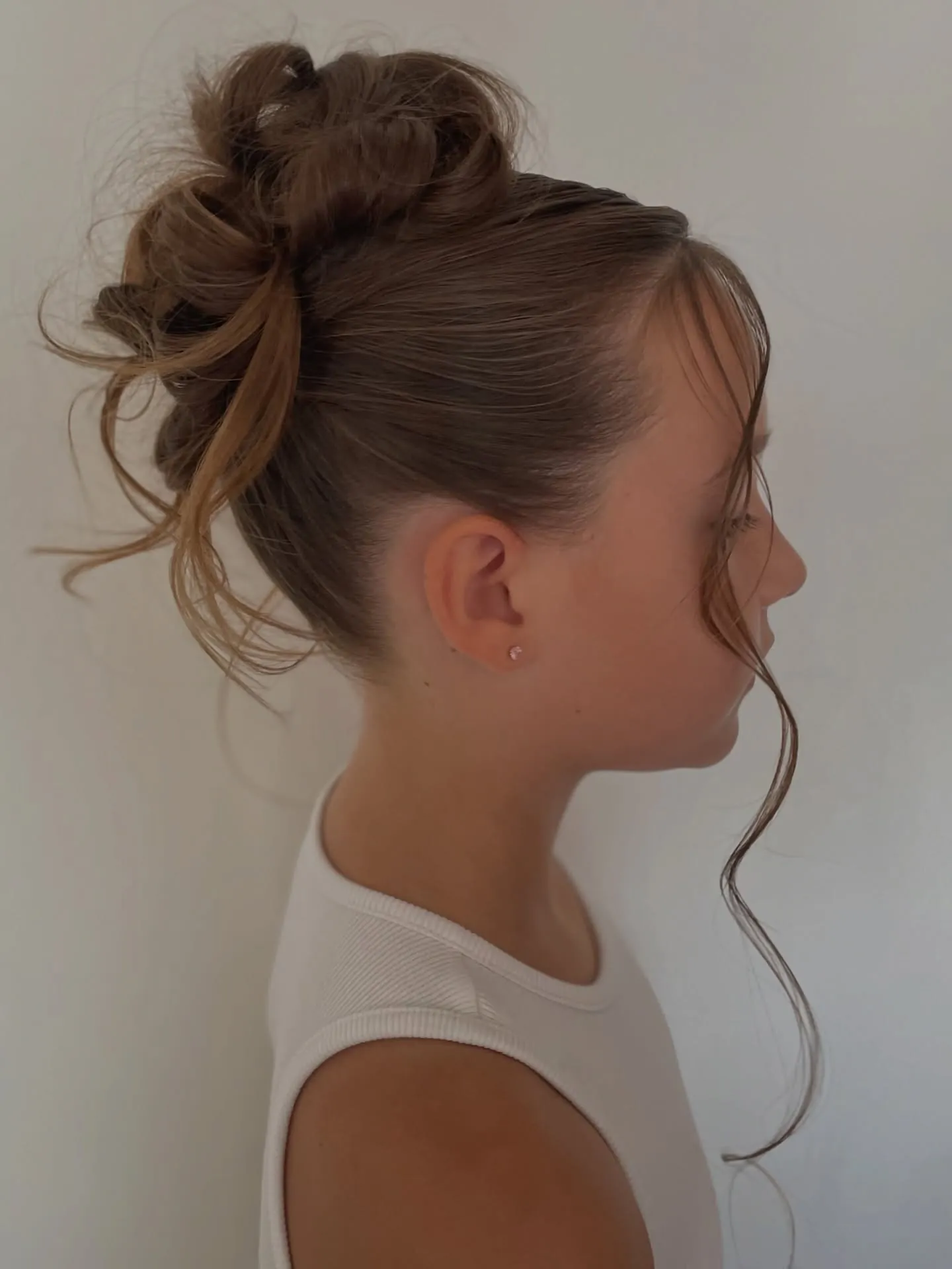 Messy high bun with loose face-framing tendrils