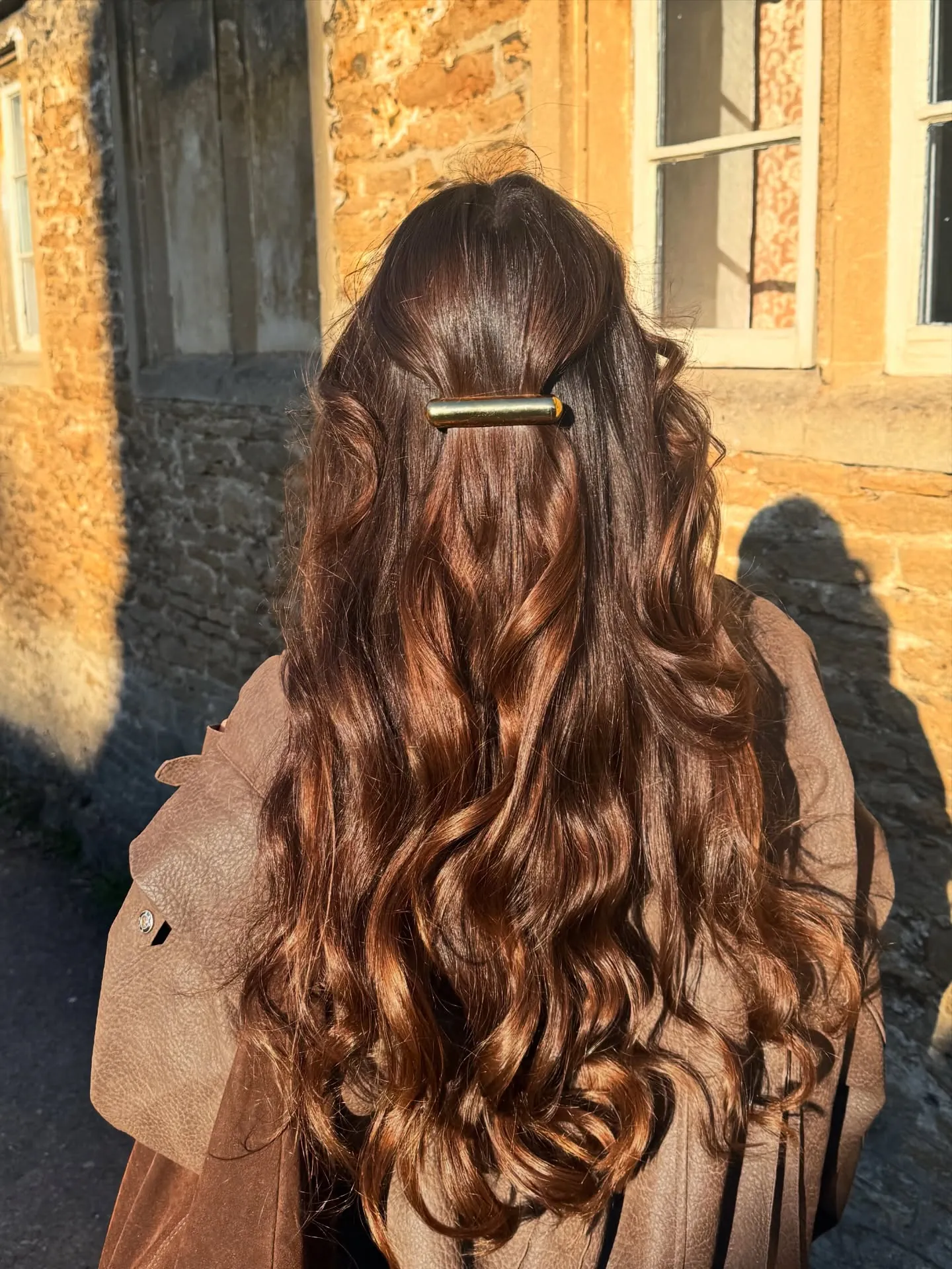 Long brown waves in a half-up style secured with a slim barrette