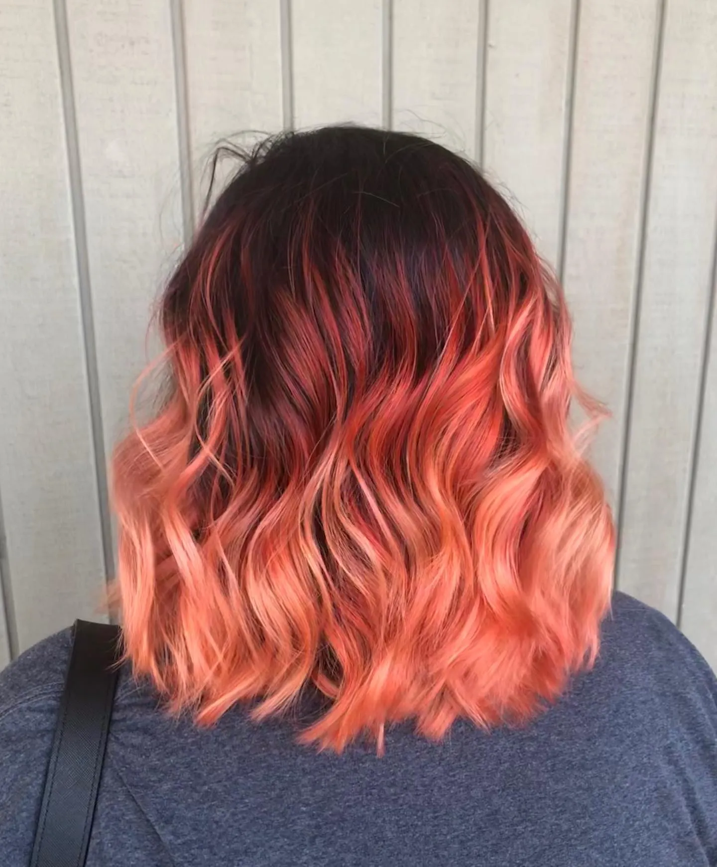 Wavy lob with dark roots fading into coral and peach ends