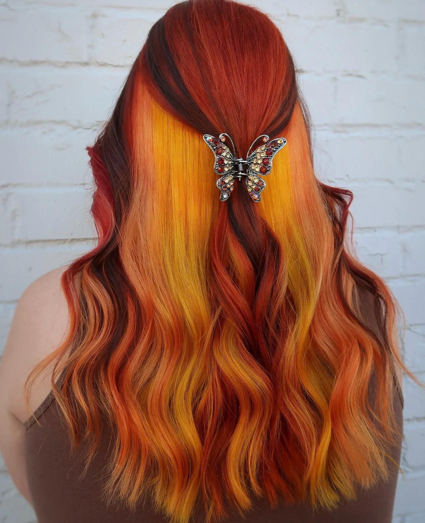 Long red, orange and yellow waves styled half-up with a butterfly clip