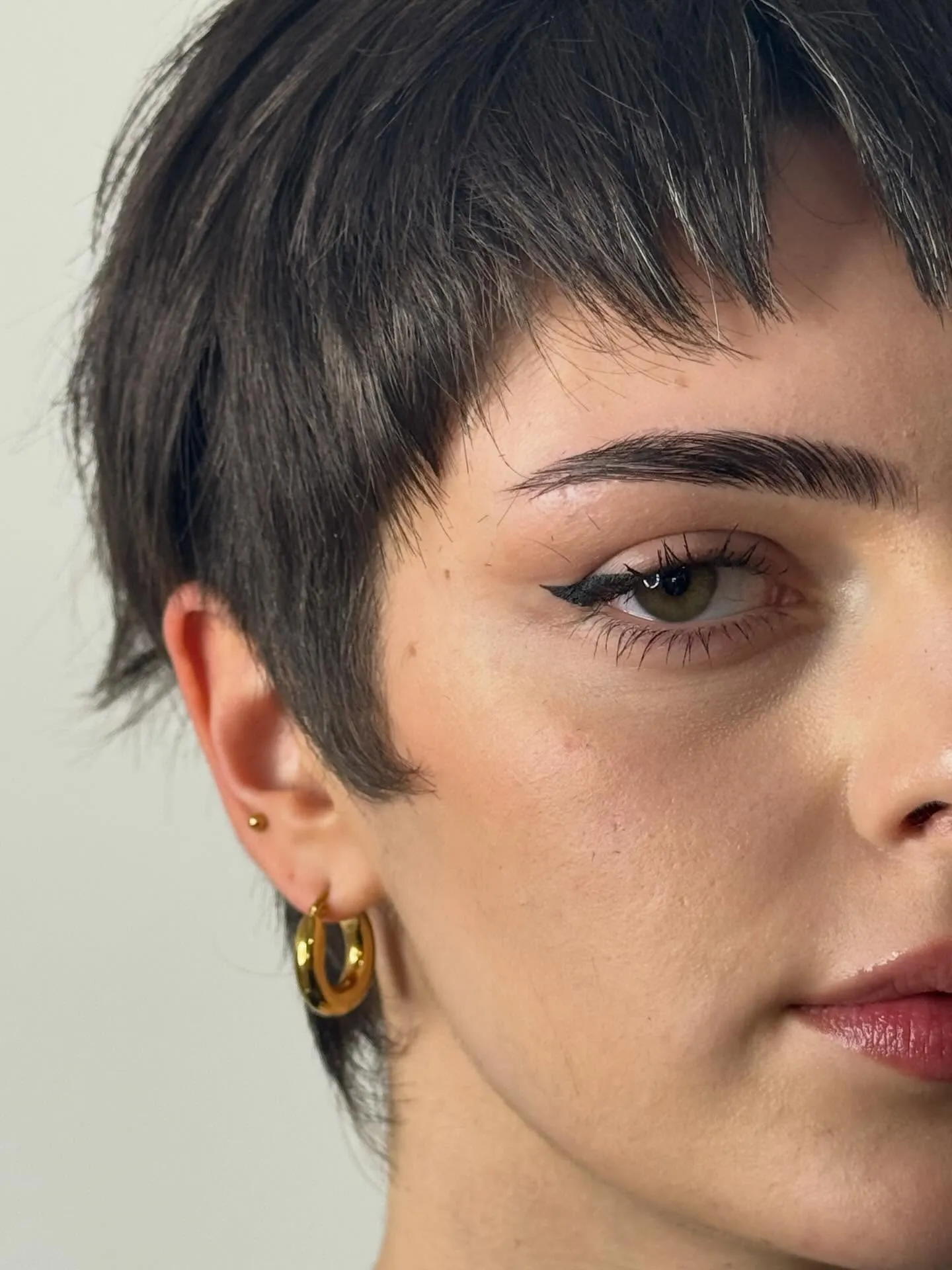 Close-cropped dark pixie with a textured micro fringe and tapered sides