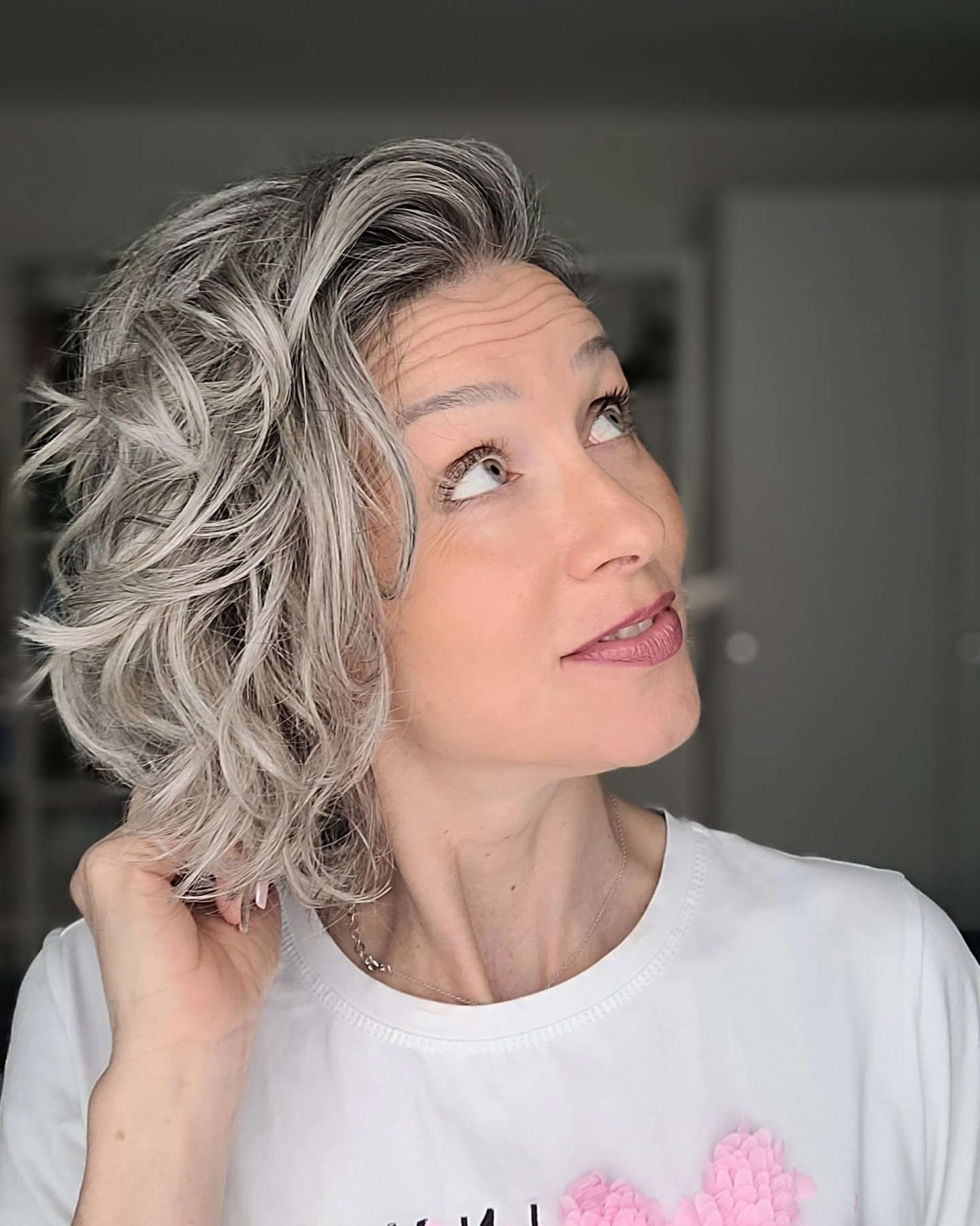 Curly gray bob with a deep side part and lifted volume
