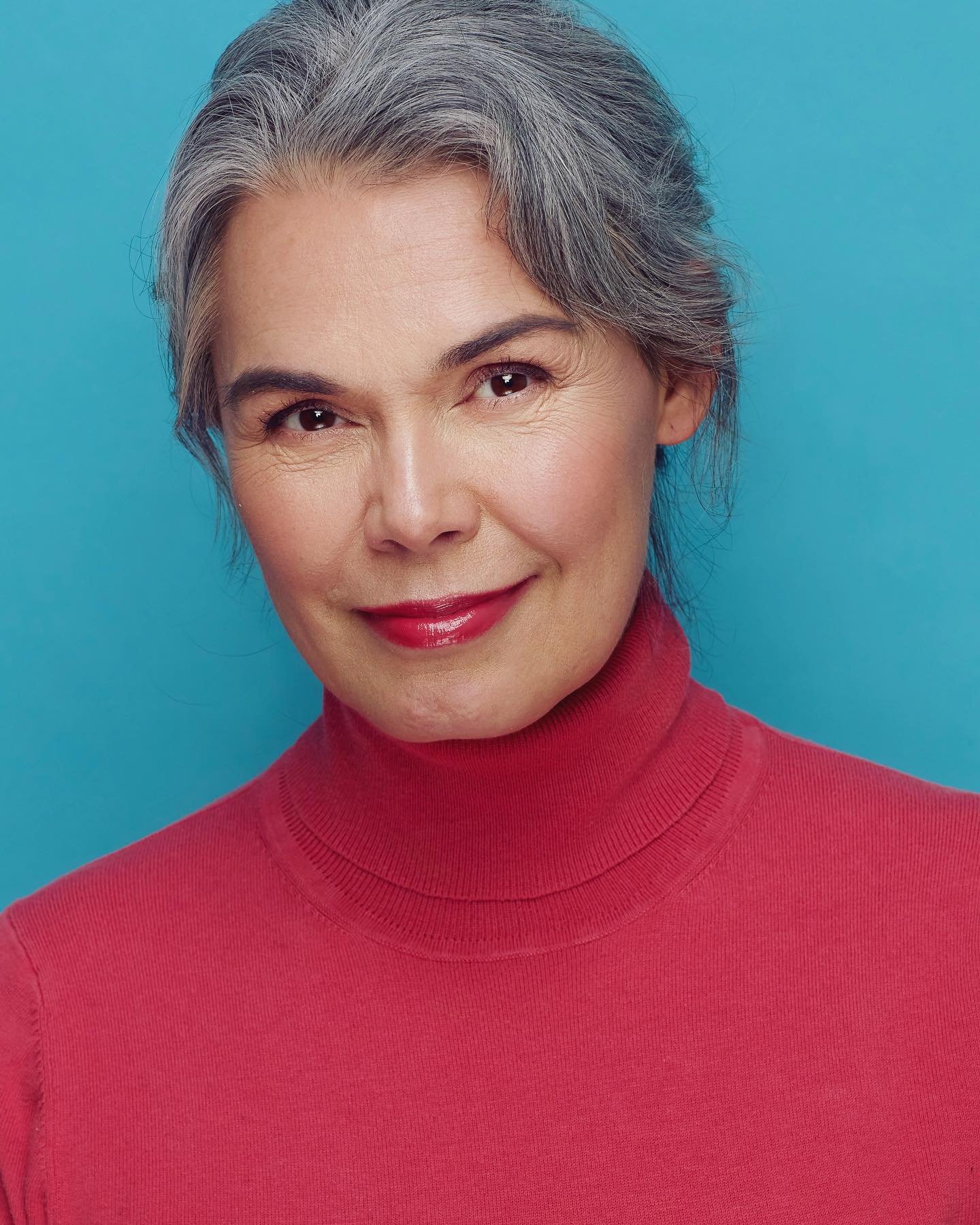 Centre-parted gray hair styled in a smooth low updo