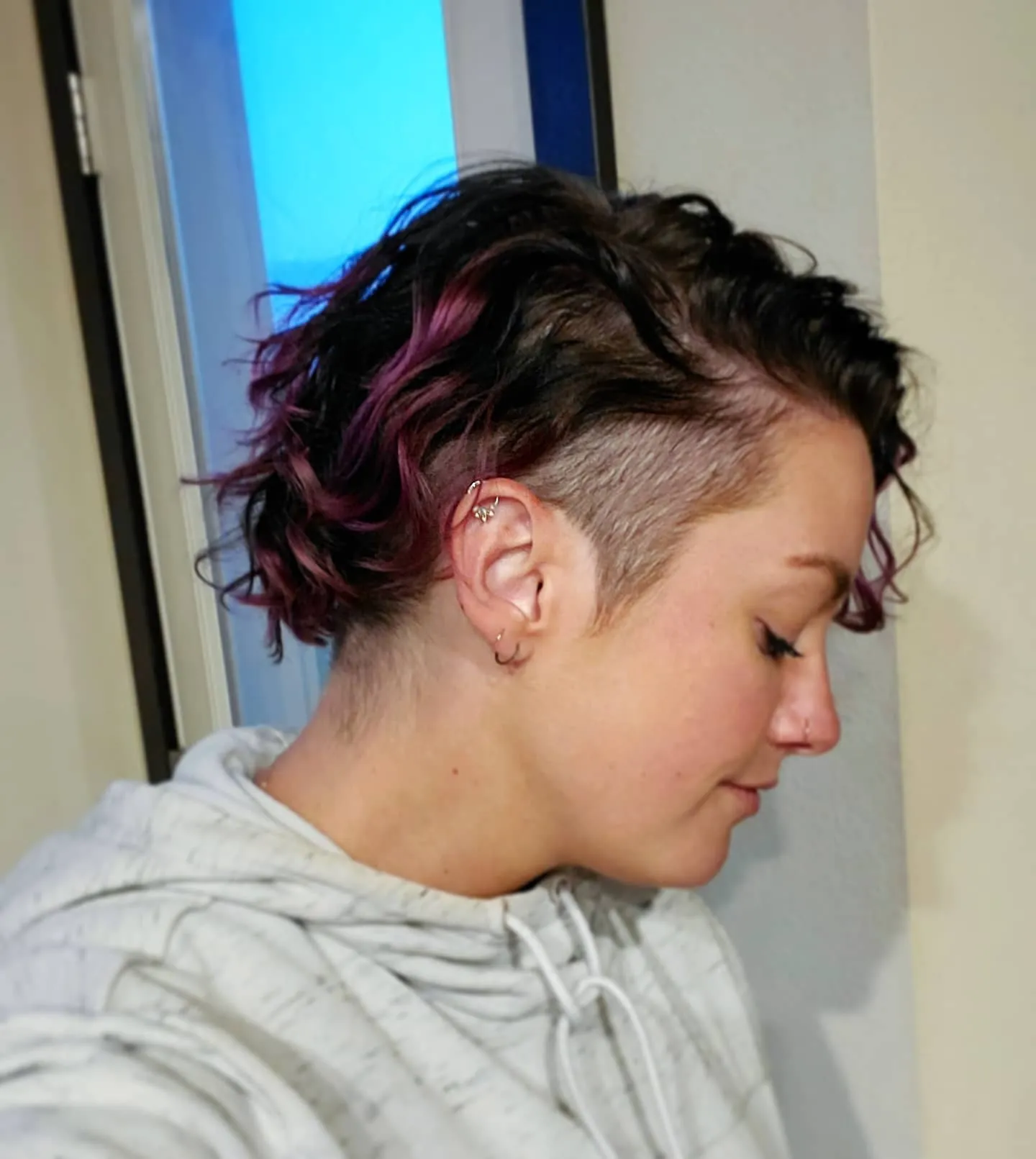 Curly pixie with shaved sides, lifted top and coloured streaks