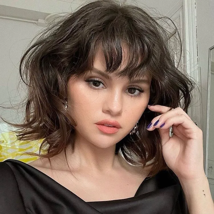 Tousled dark wavy lob with wispy fringe and face-framing layers