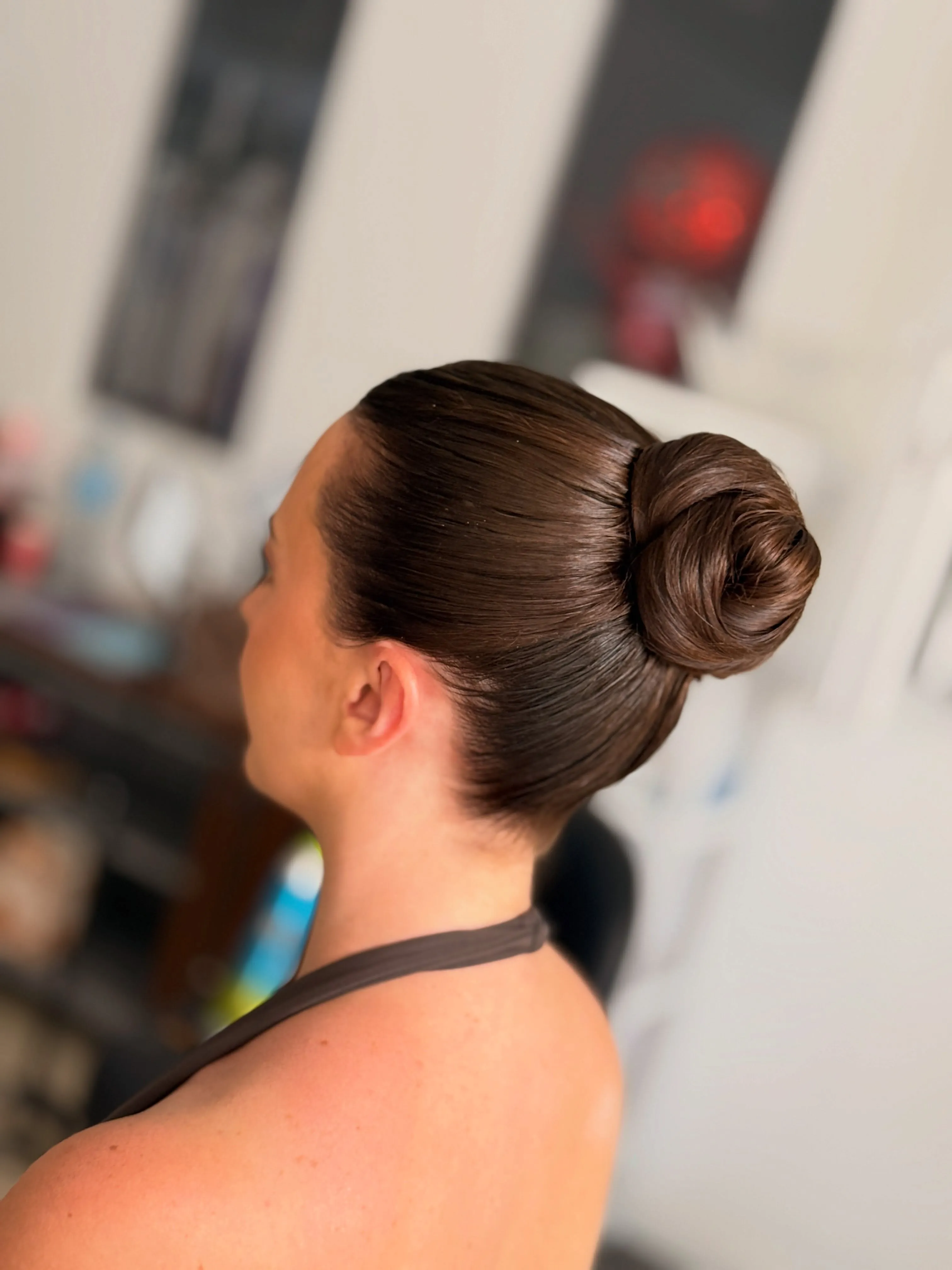 Sleek dark high knot bun with a smooth polished finish