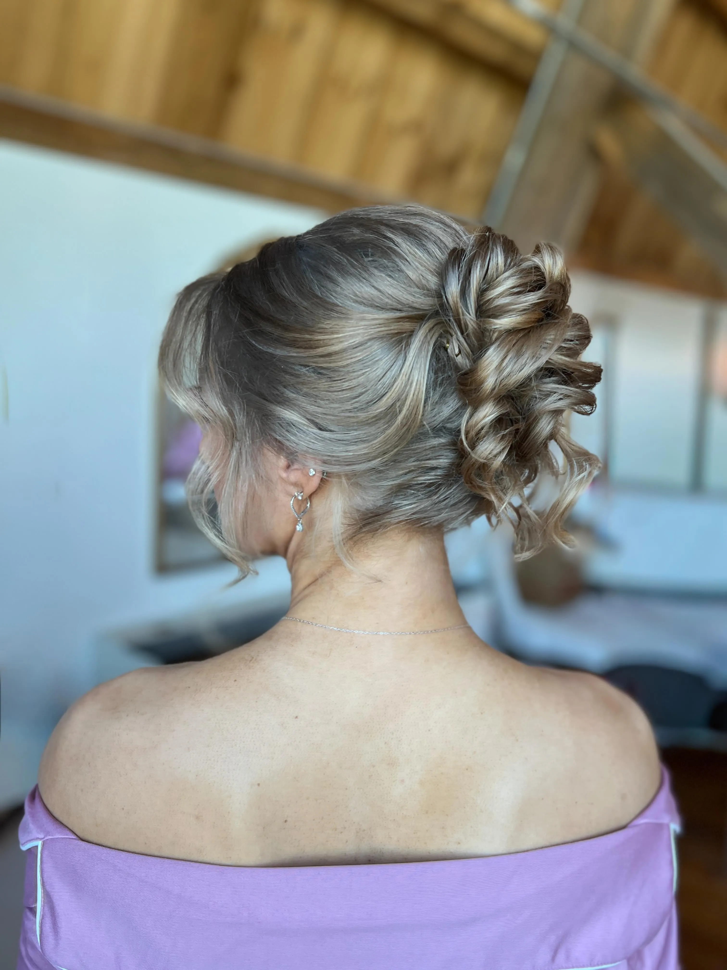 Braided blonde high bun with woven sections and curled ends