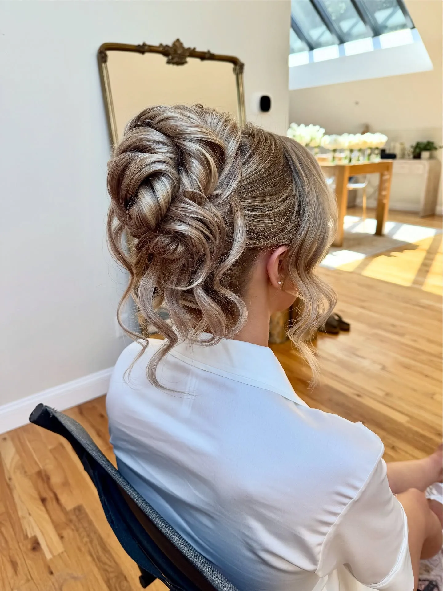 Blonde curled high updo with braided texture and loose ringlets