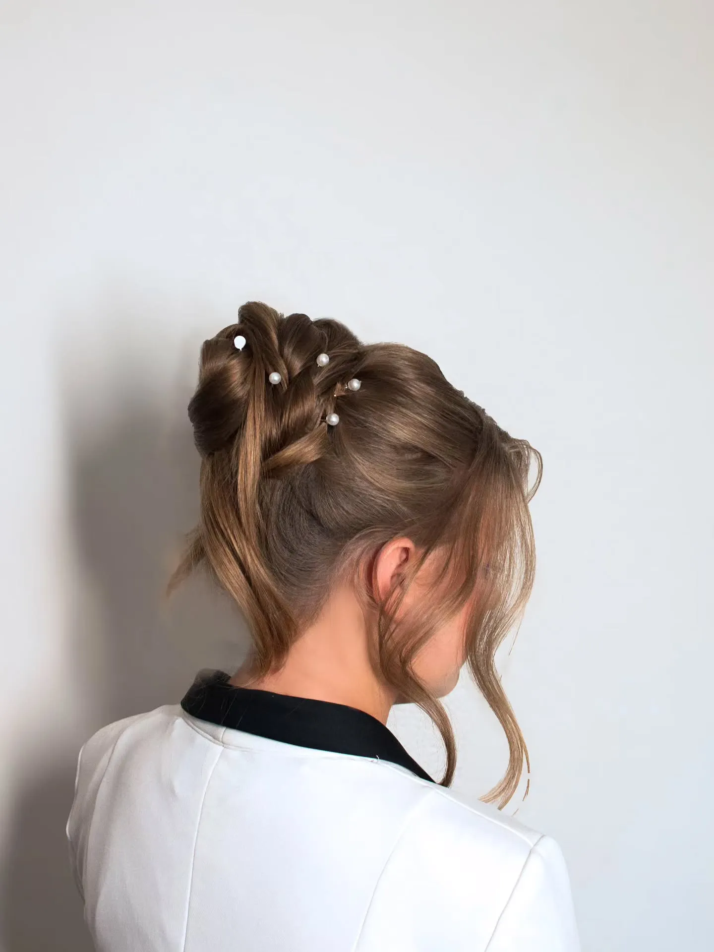 Wrapped brown high bun with scattered pearl details and loose front pieces