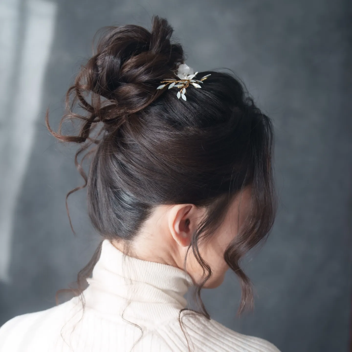 Soft dark high bun with a delicate hair vine and curled side pieces