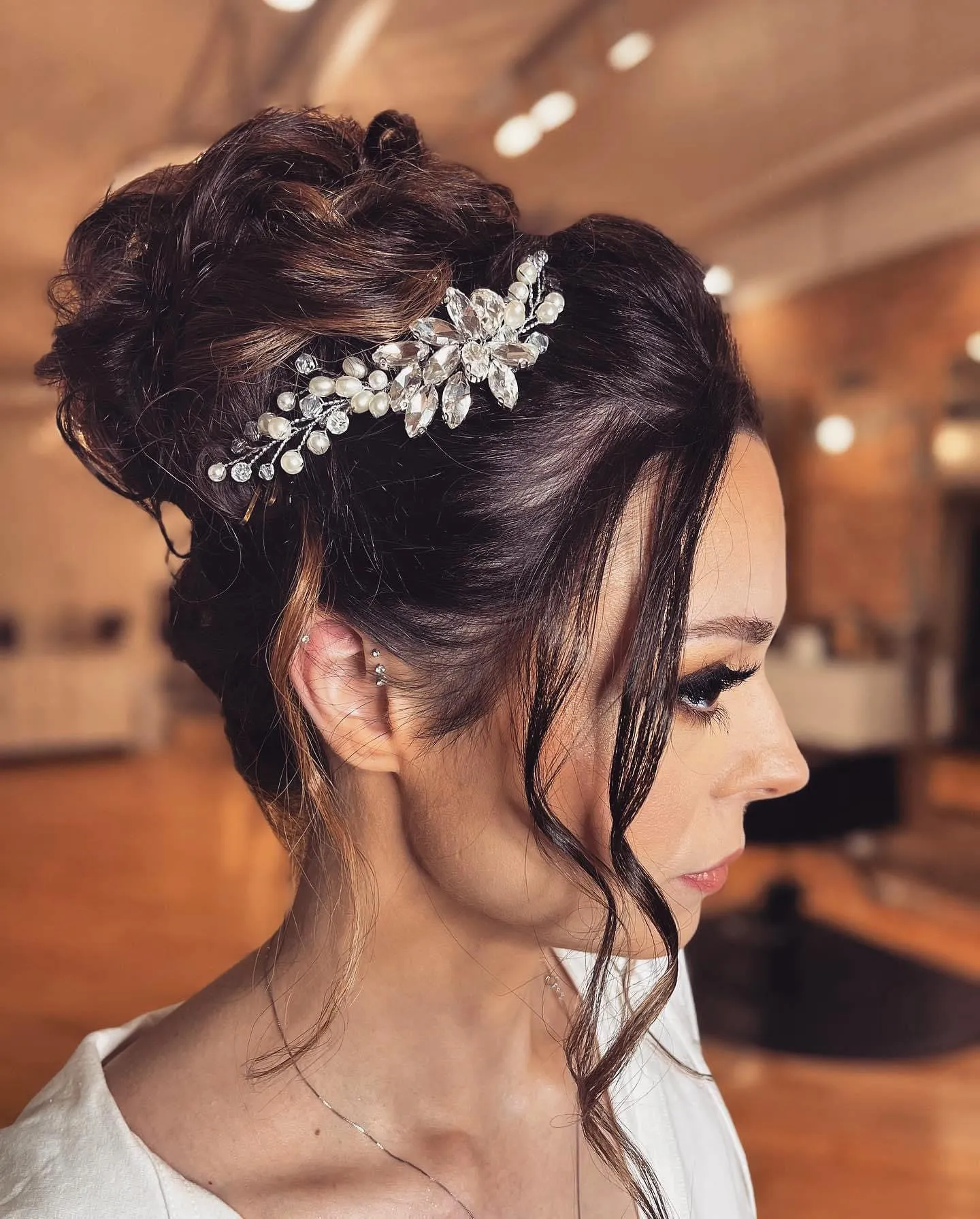 Textured dark high bun with a crystal comb and face-framing pieces