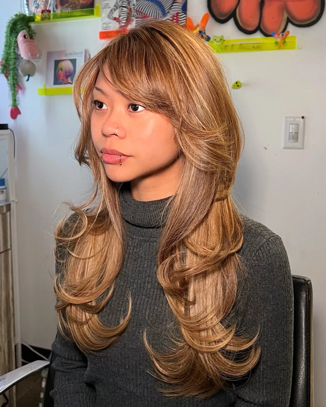 Long layered hair with curtain bangs and warm highlights