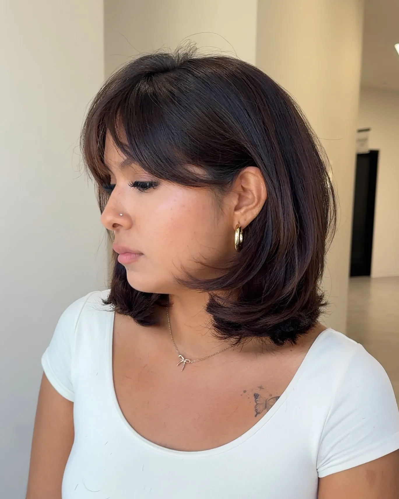 Shoulder-length layered bob with curtain bangs and flicked ends