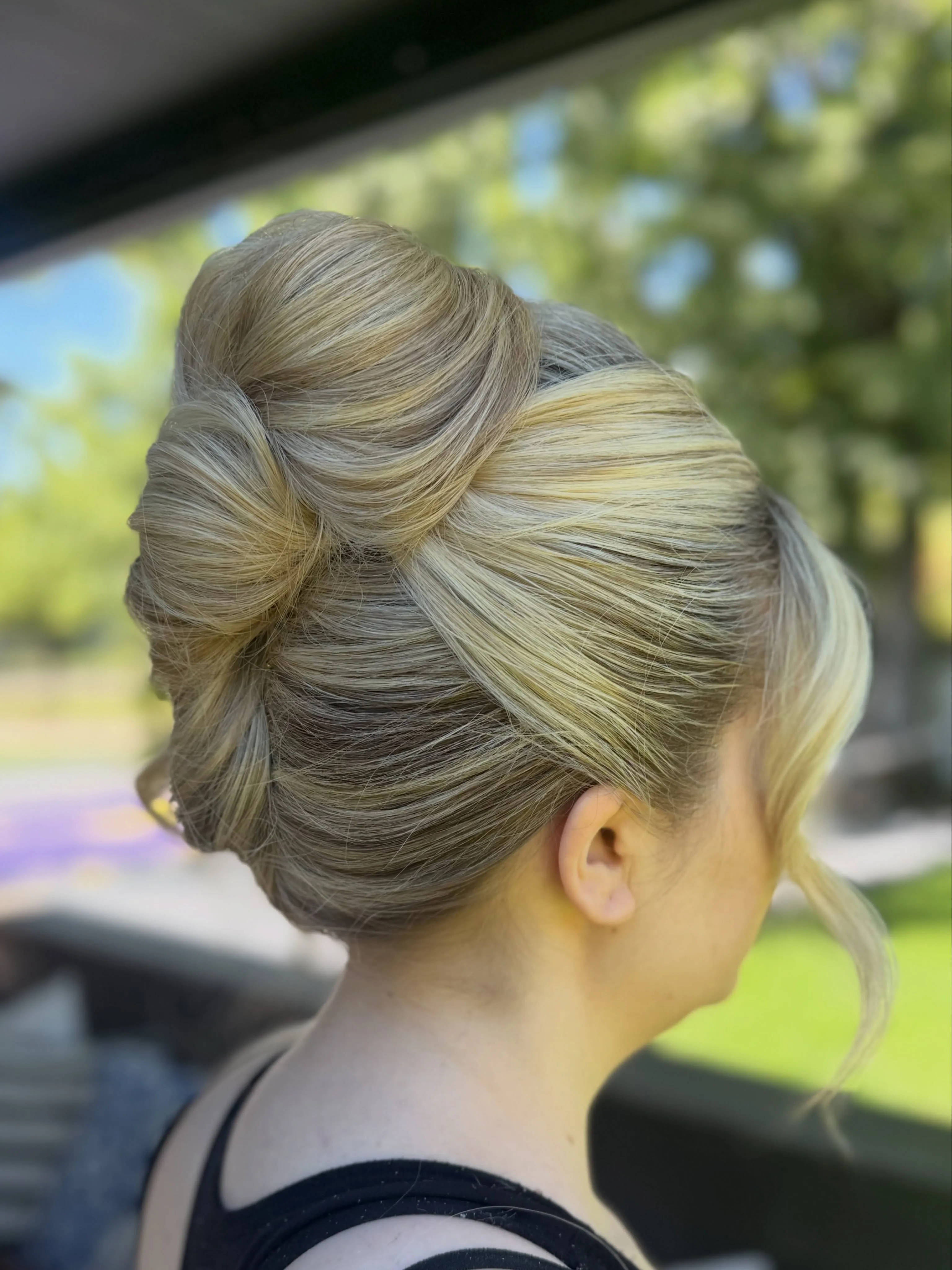 Sculpted high wedding updo with smooth overlapping loops and a loose front tendril