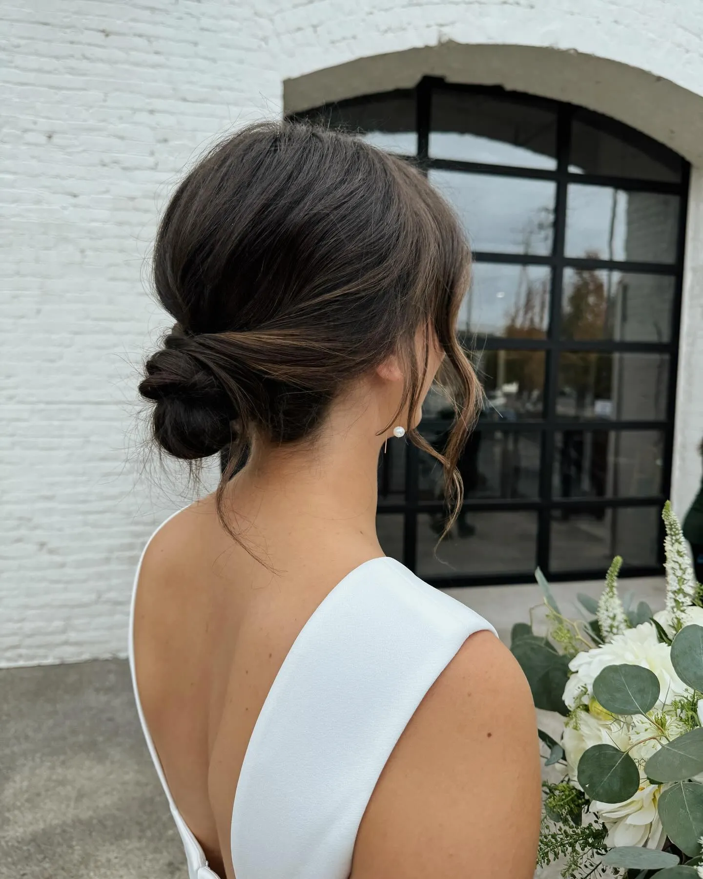 Minimal low wedding knot with a centre part and soft curled face-framing pieces