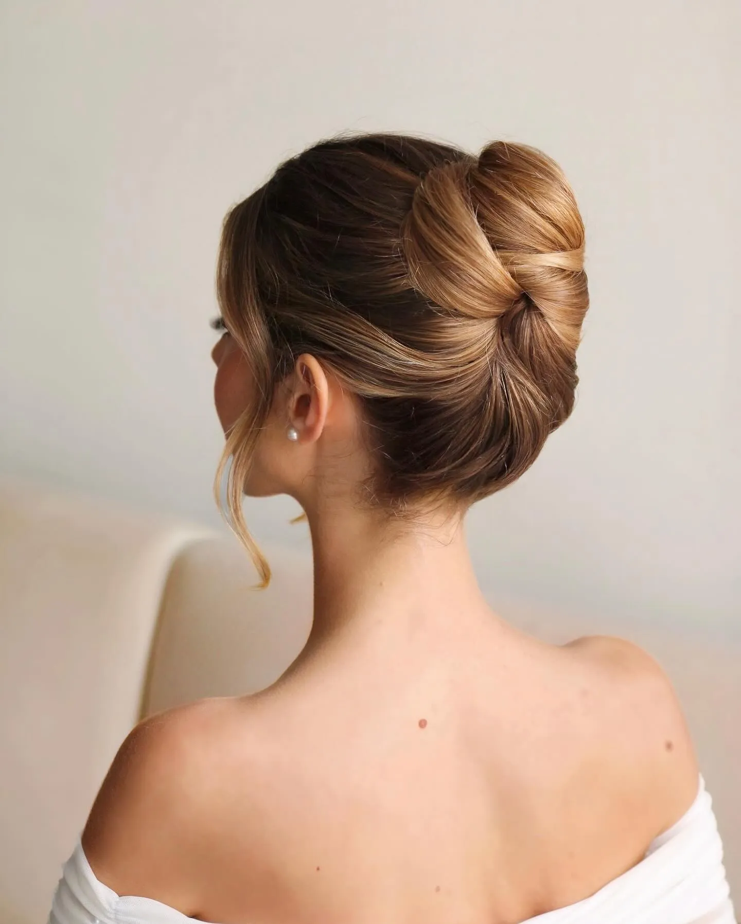 Polished bow-shaped French twist with smooth sides and a curled face-framing piece