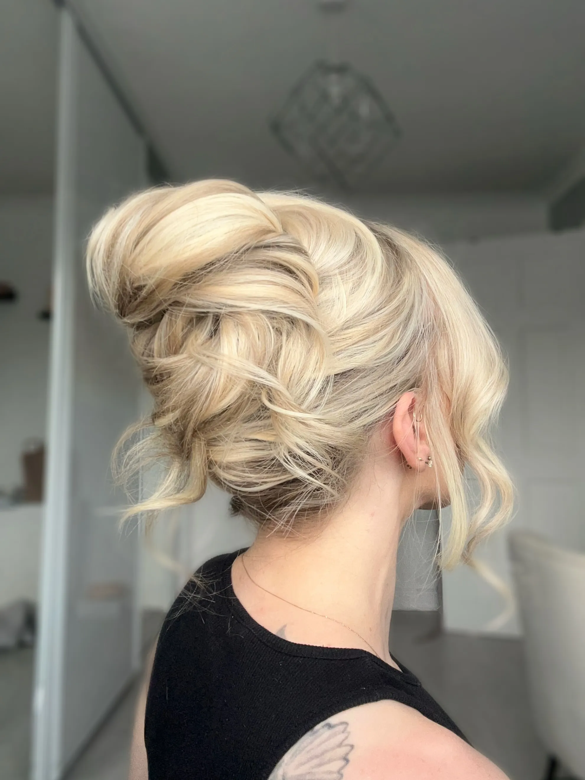 Voluminous high wedding updo with broad twists, loose texture and curled front pieces