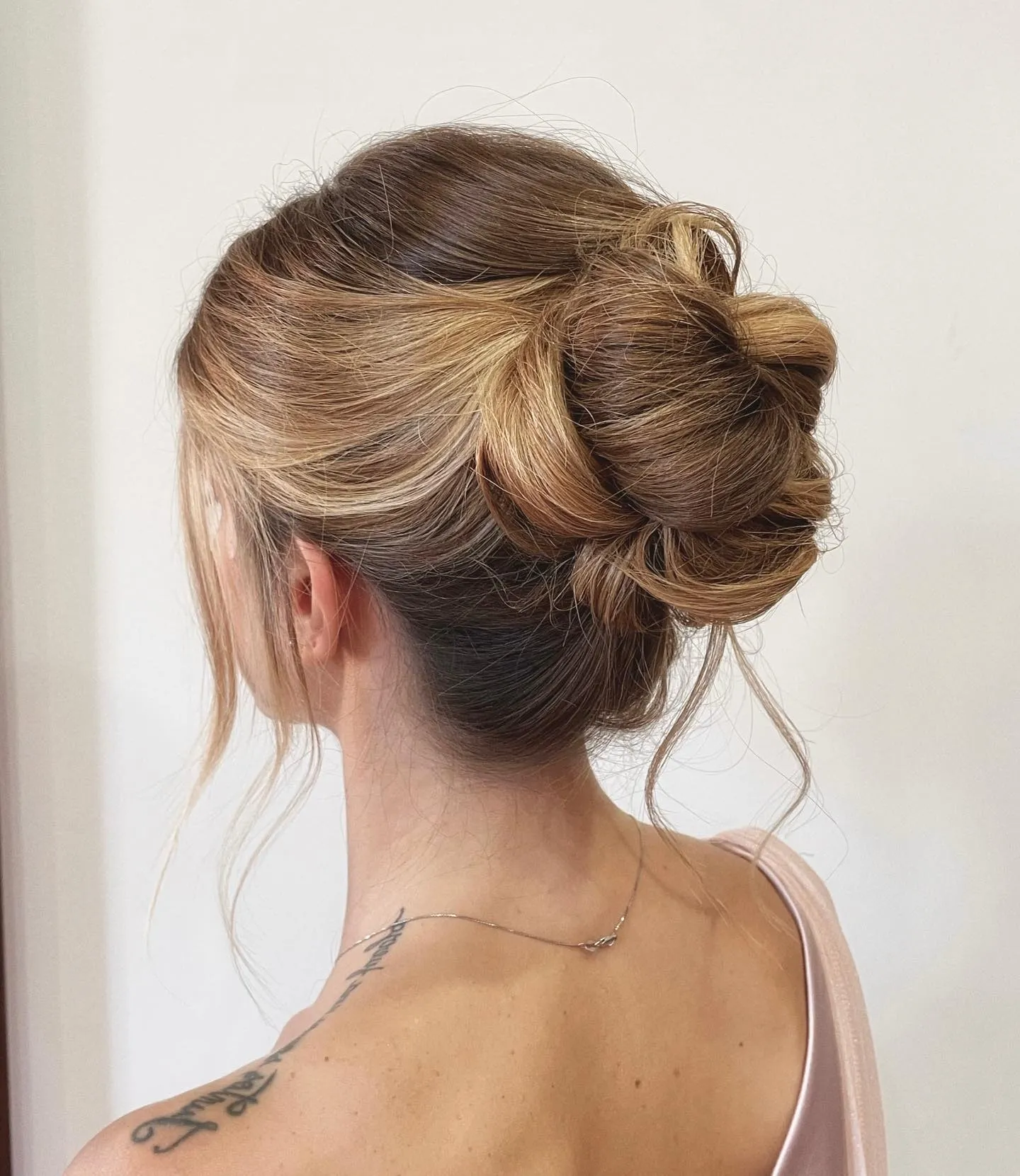Loose looped wedding bun with soft crown volume and long face-framing pieces