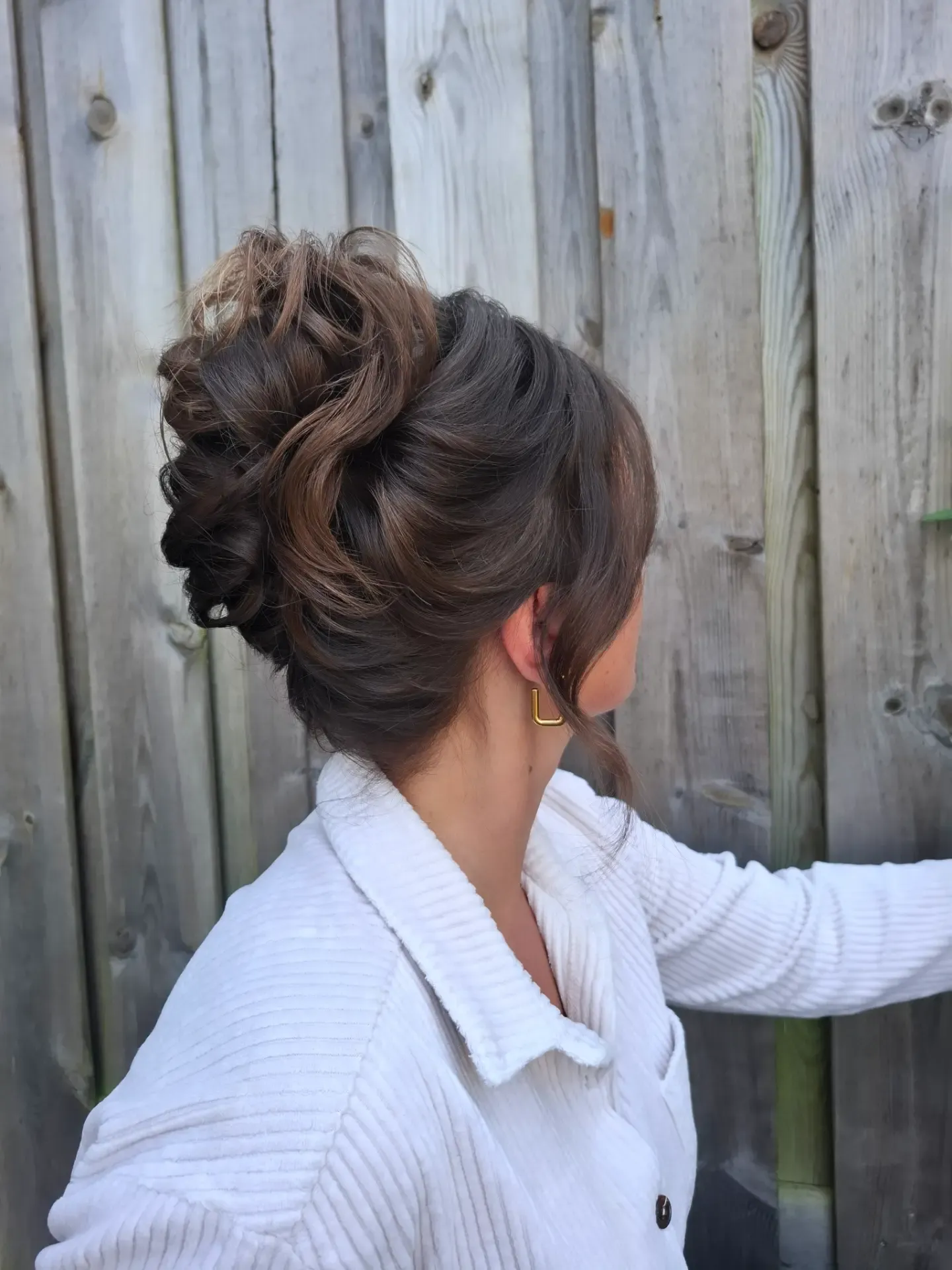 Textured high messy bun on dark brown hair with loose face-framing strands