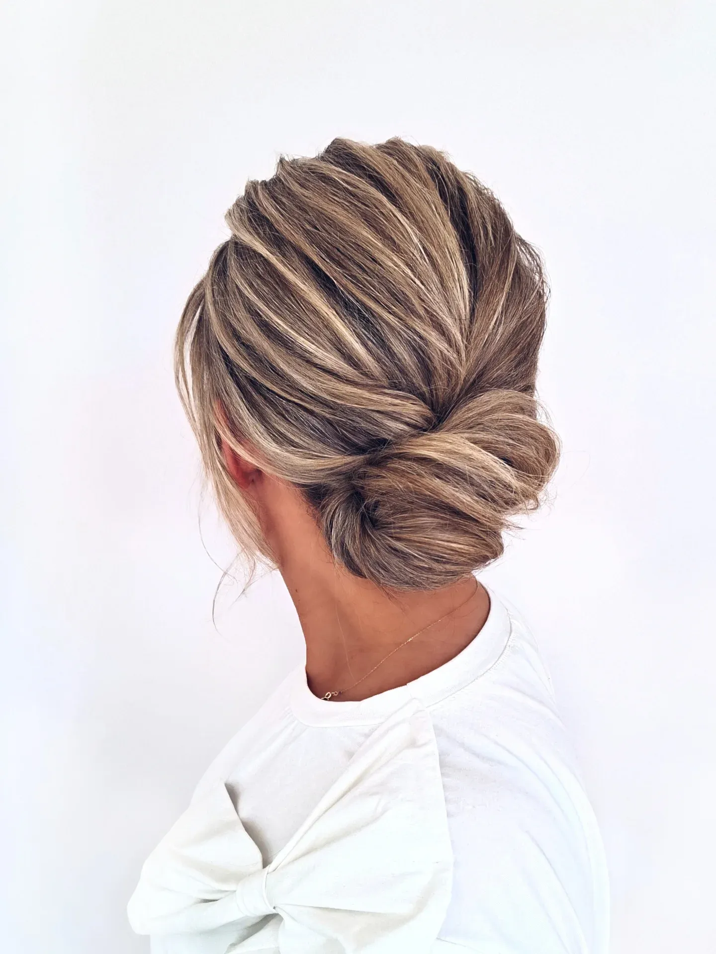 Twisted low blonde chignon with polished side sections