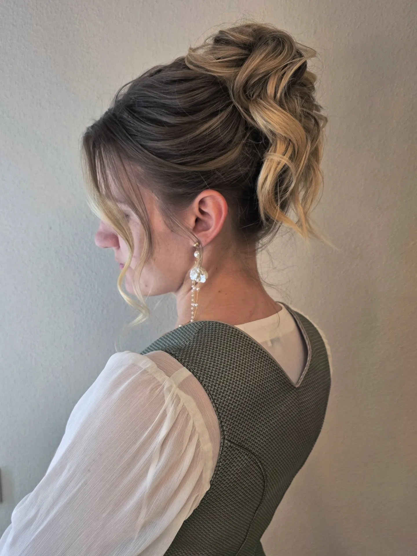 Curly high blonde bun with loose tendrils around the face