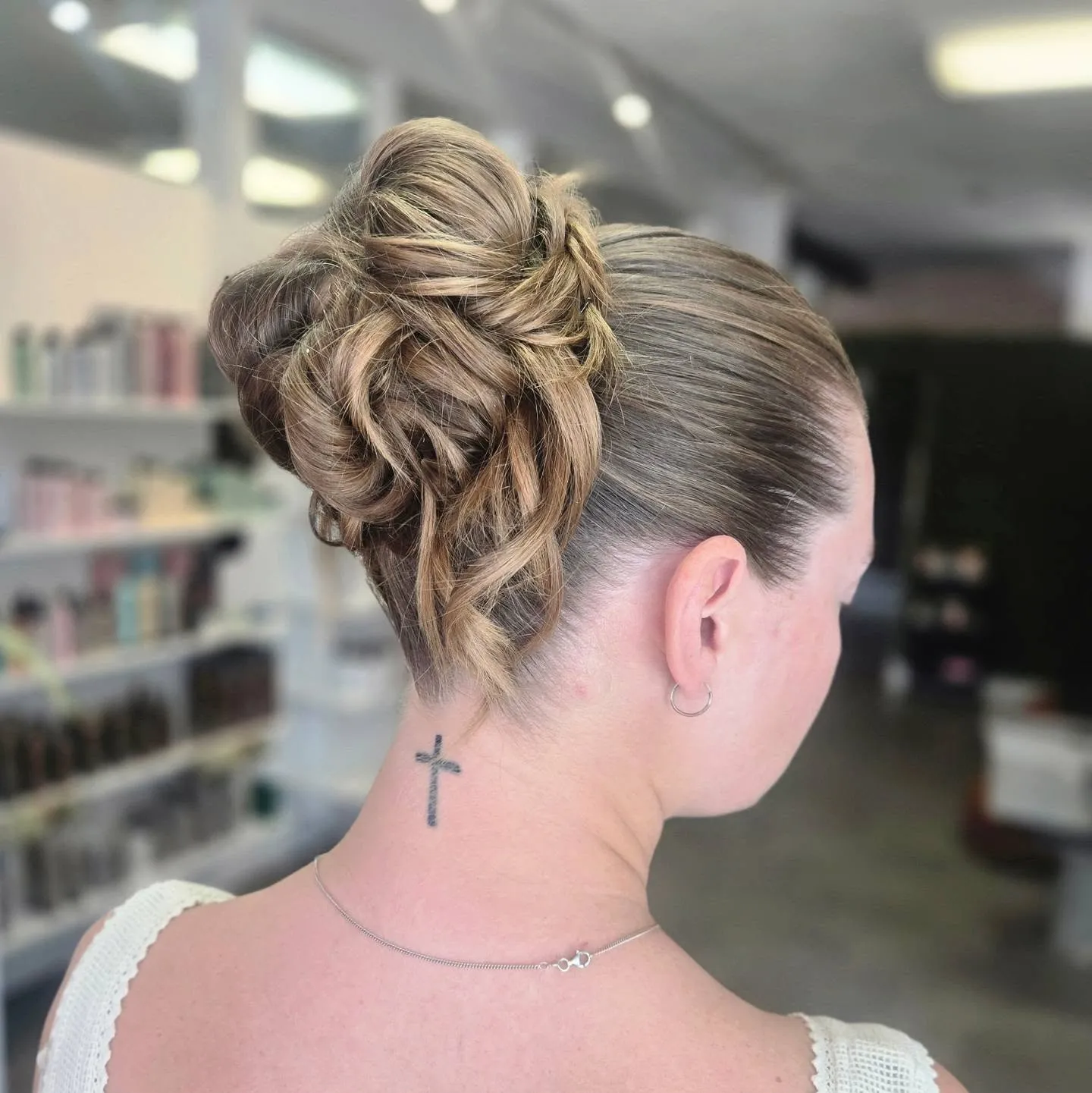 Sculpted high blonde bun with defined curled loops and sleek sides