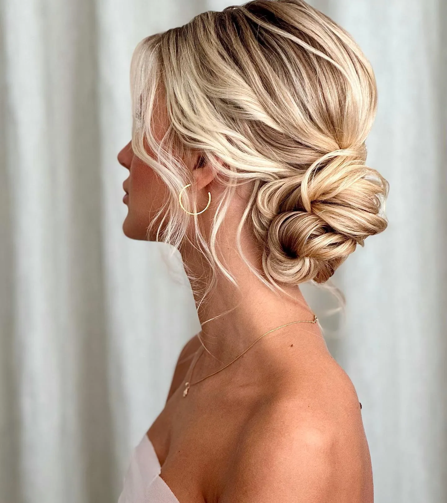 Twisted low messy bun on blonde hair with soft front tendrils