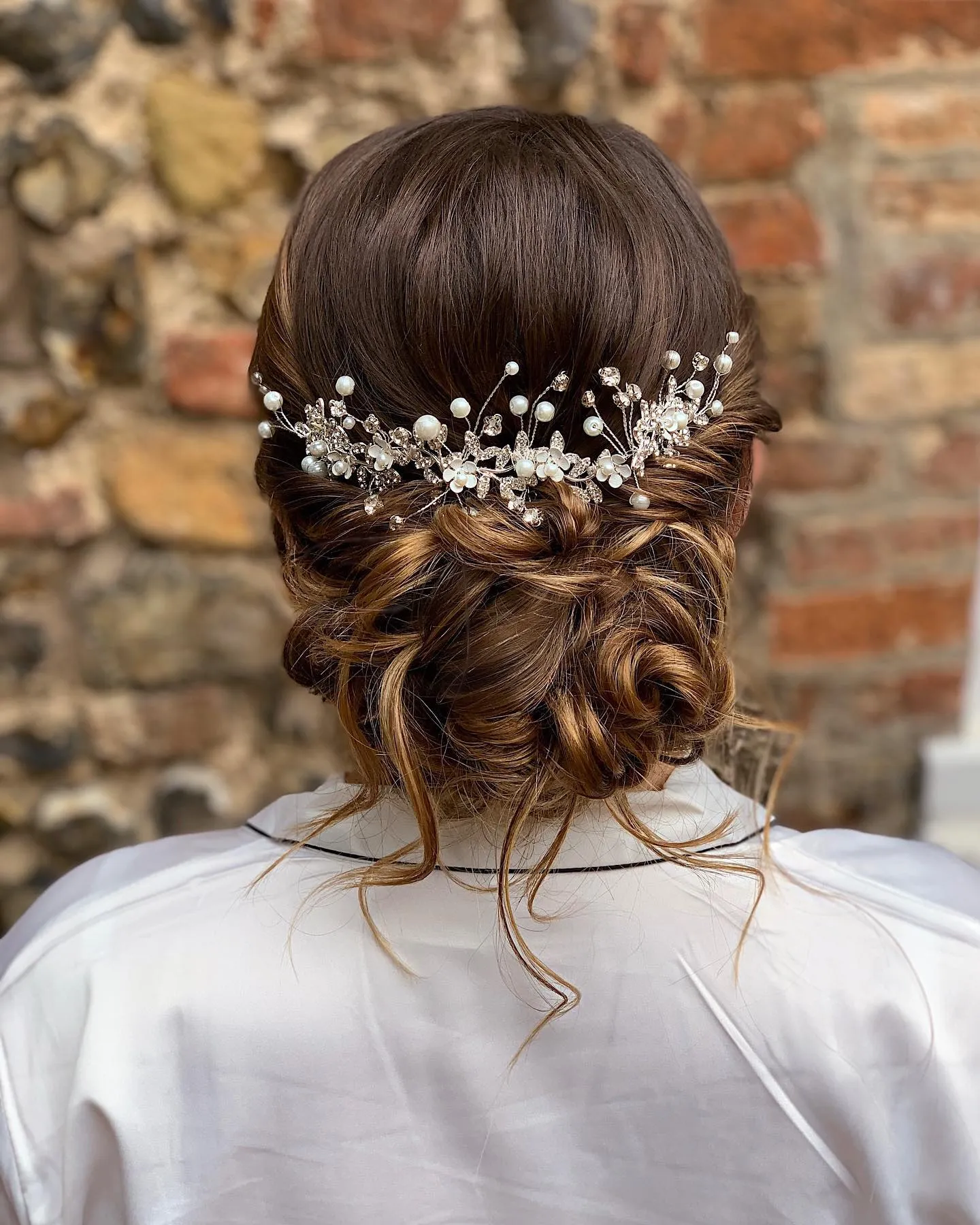 Curly low wedding bun with pearl and crystal hairpiece