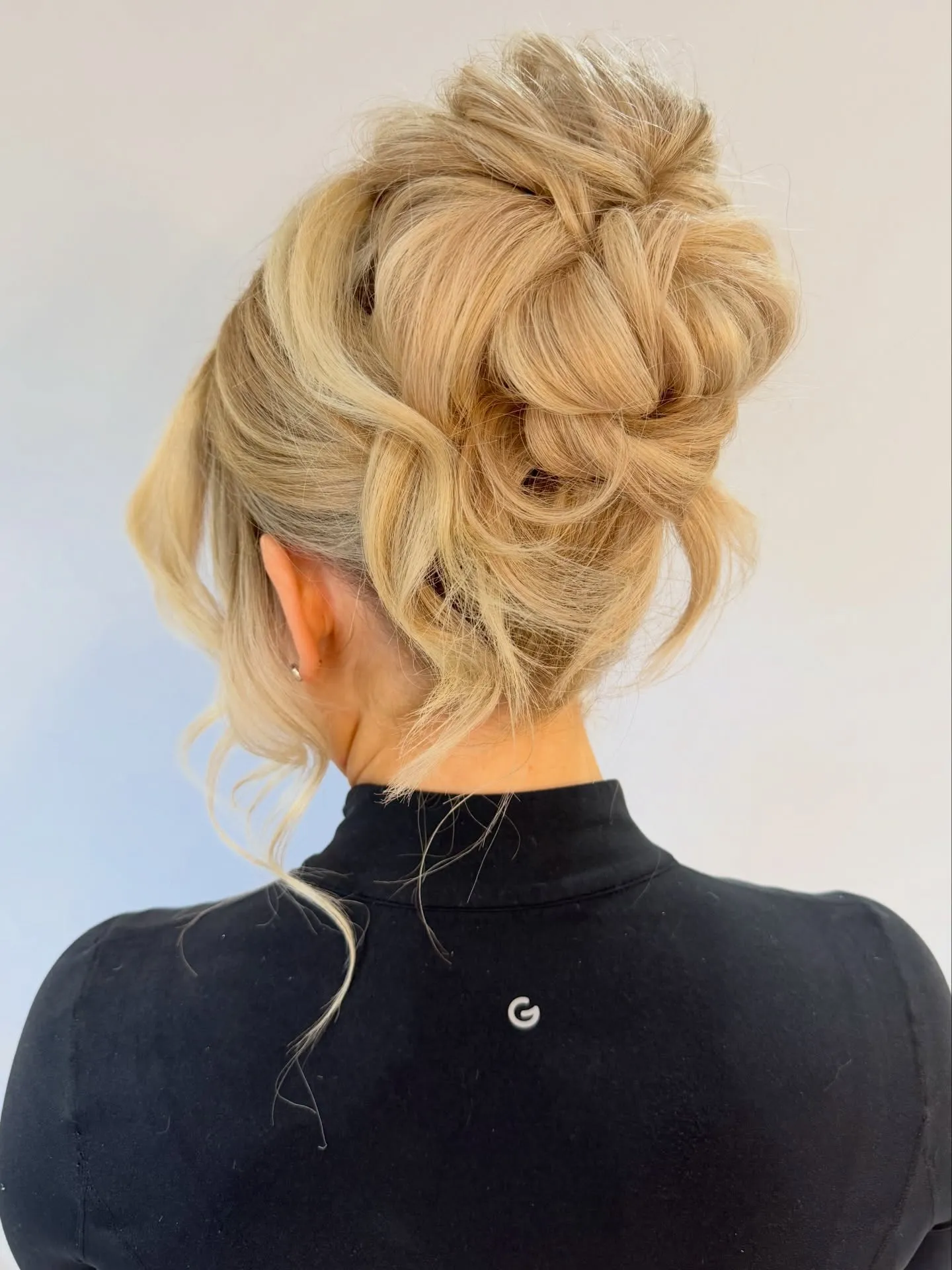 Tousled high blonde bun with loose wispy pieces