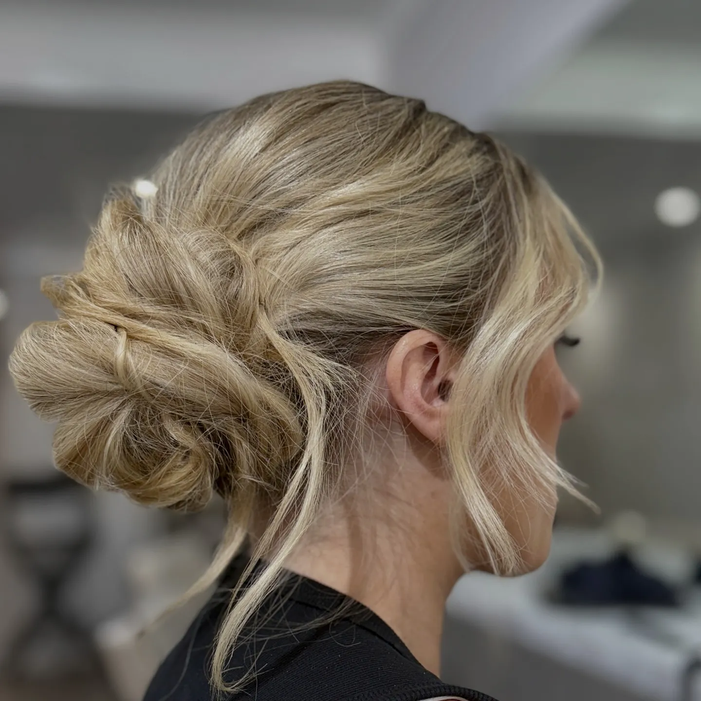 Loose low blonde bun with wispy face-framing pieces