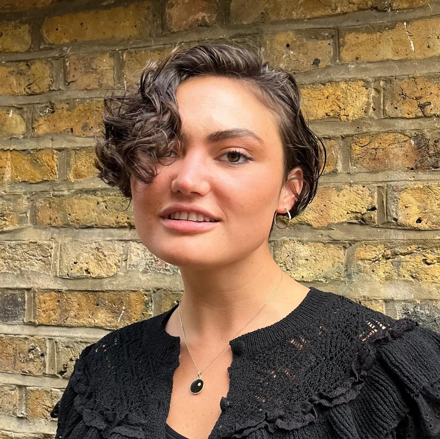 Short curly micro bob with a deep side part and sculpted waves