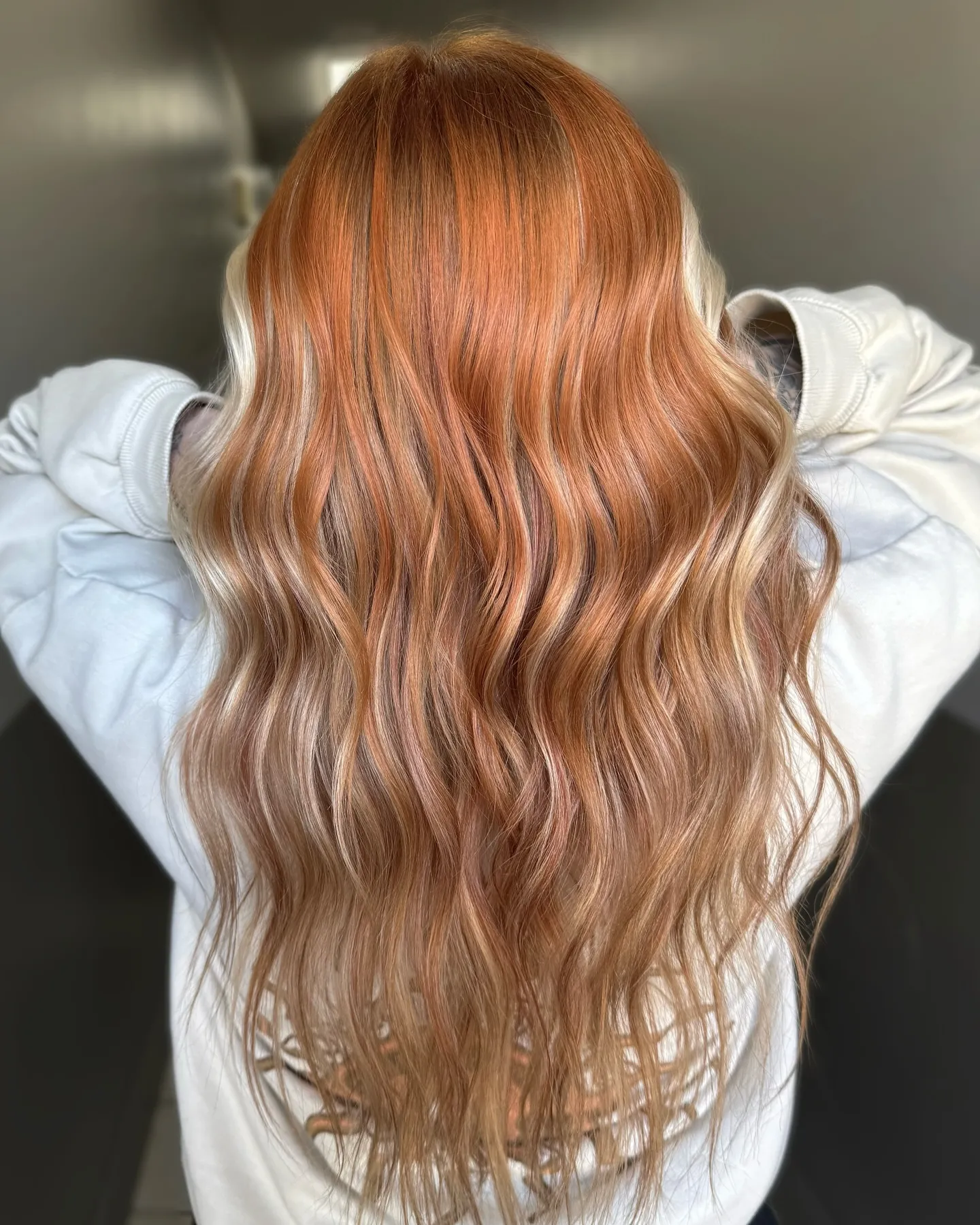 Long wavy hair with copper roots melting into pale blonde lengths