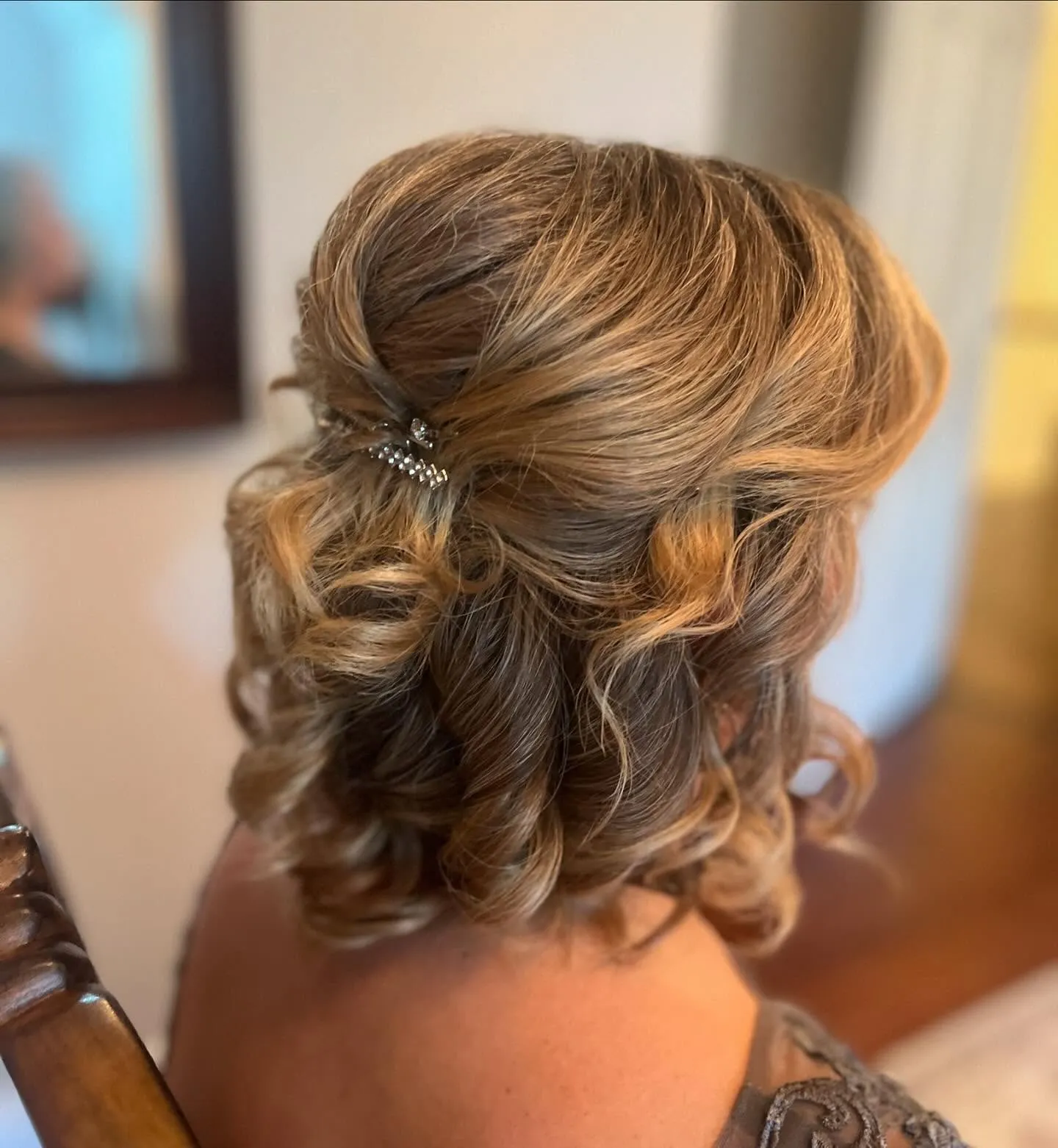 Shoulder-length brown curls pinned half up with a small clip