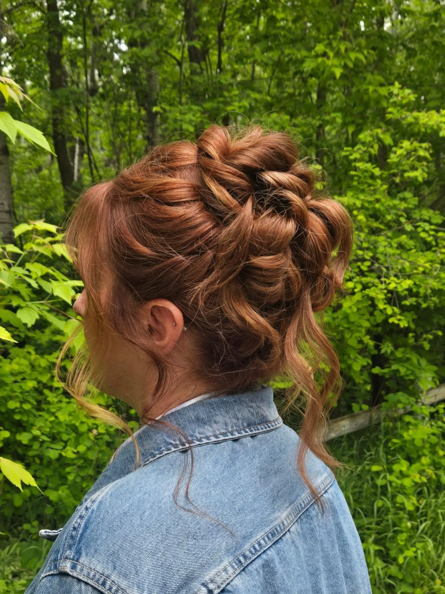 Tousled high bun on red hair with loose tendrils
