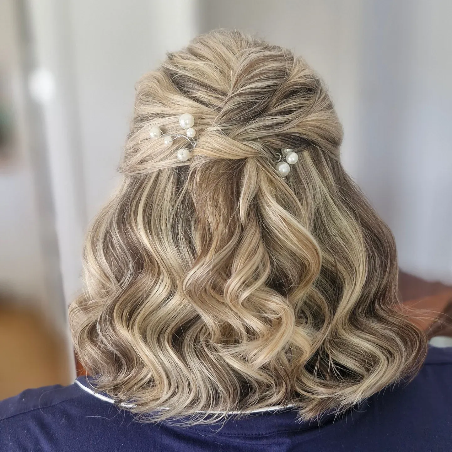 Short blonde wavy bob styled half up with pearl pins