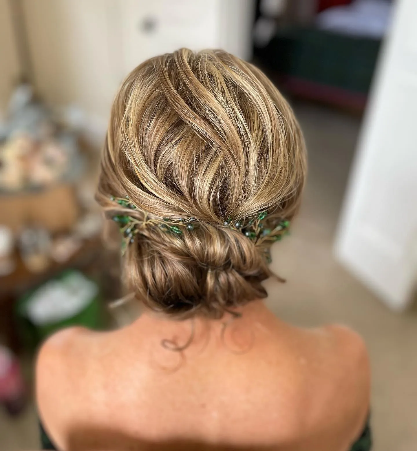 Low rolled bun with a green leafy hair accessory