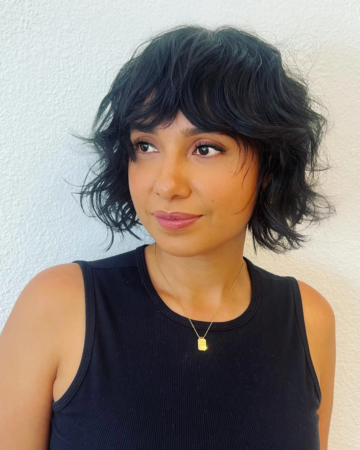 Tousled dark razor cut bob with shaggy layers and full fringe