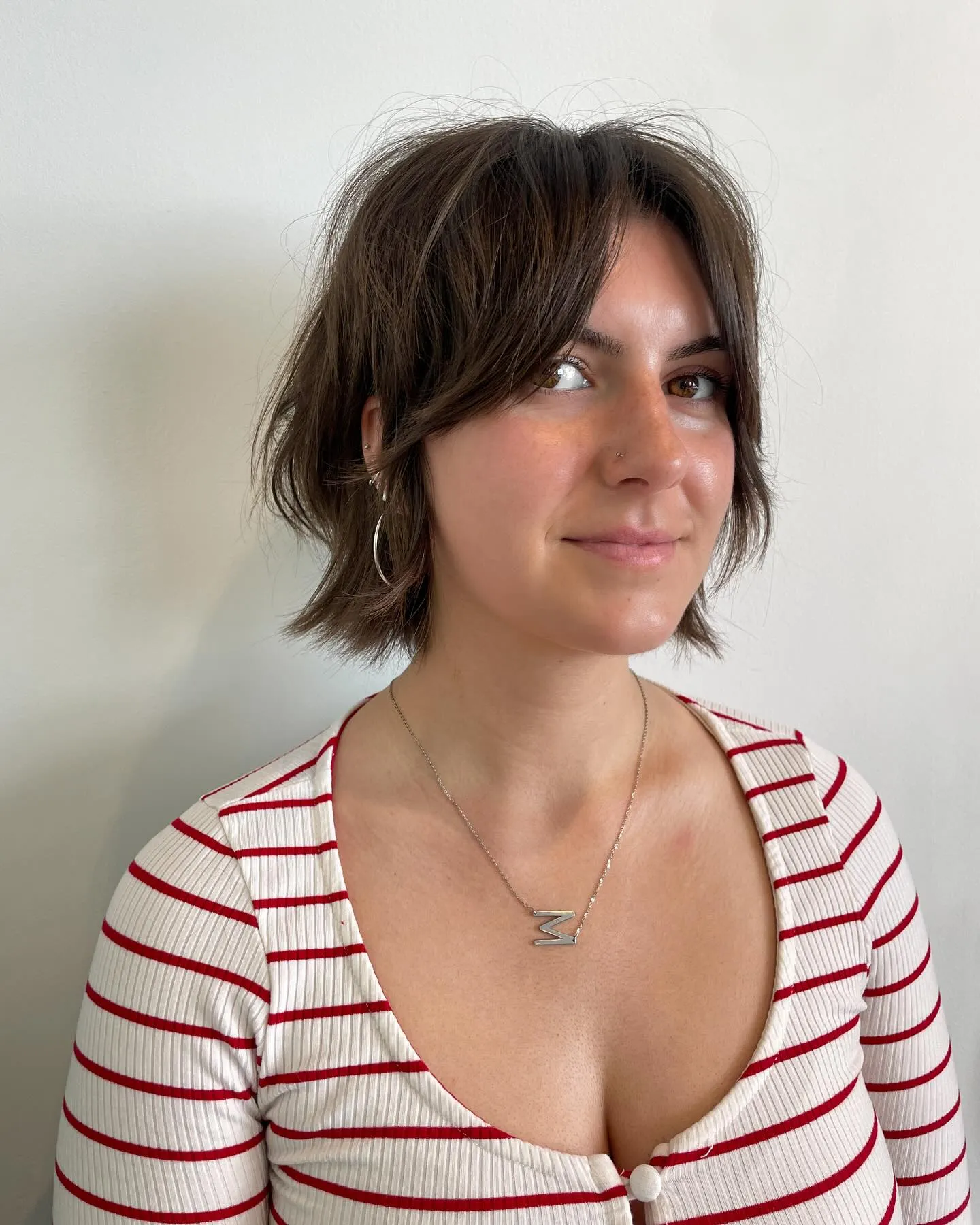 Short brown razor cut bob with airy layers and centre-swept fringe