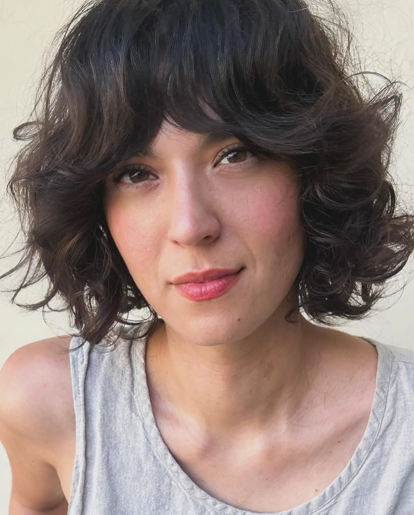 Dark curly razor cut bob with layered volume and sweeping fringe