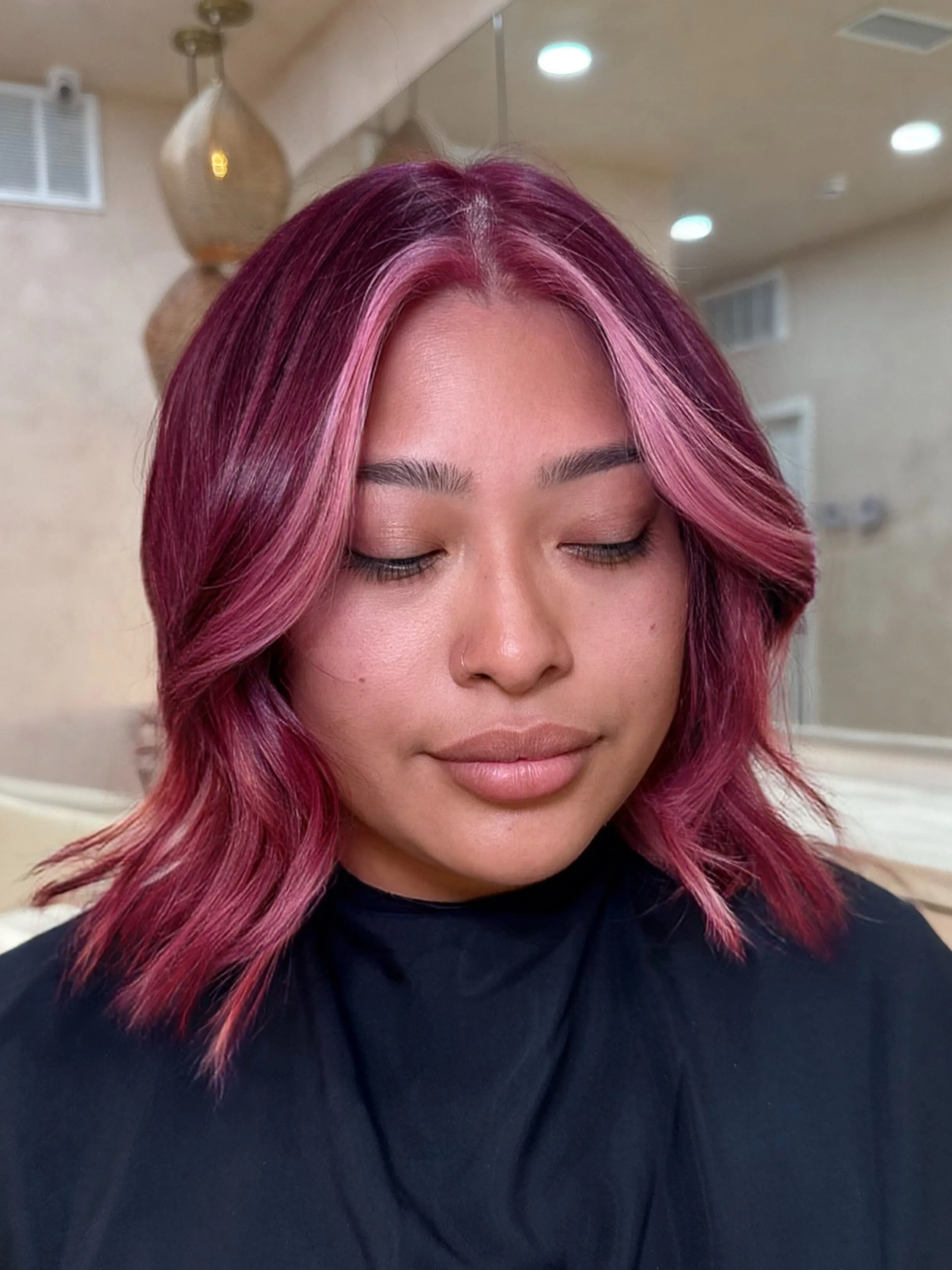 Shoulder-length pink-red wavy lob with brighter face-framing pieces