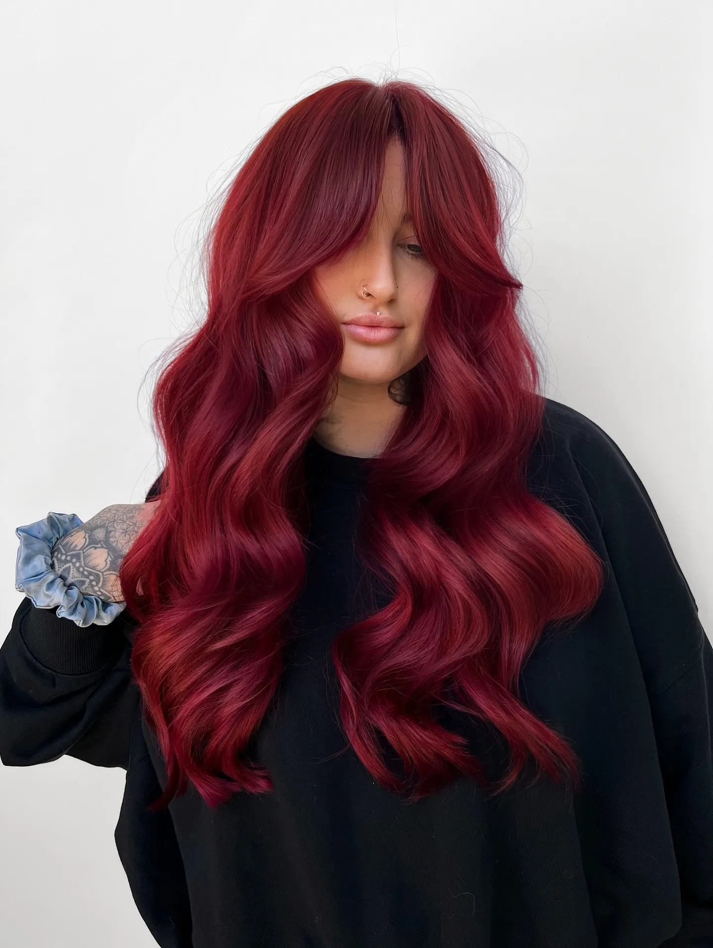 Long ruby-red waves with soft curtain bangs